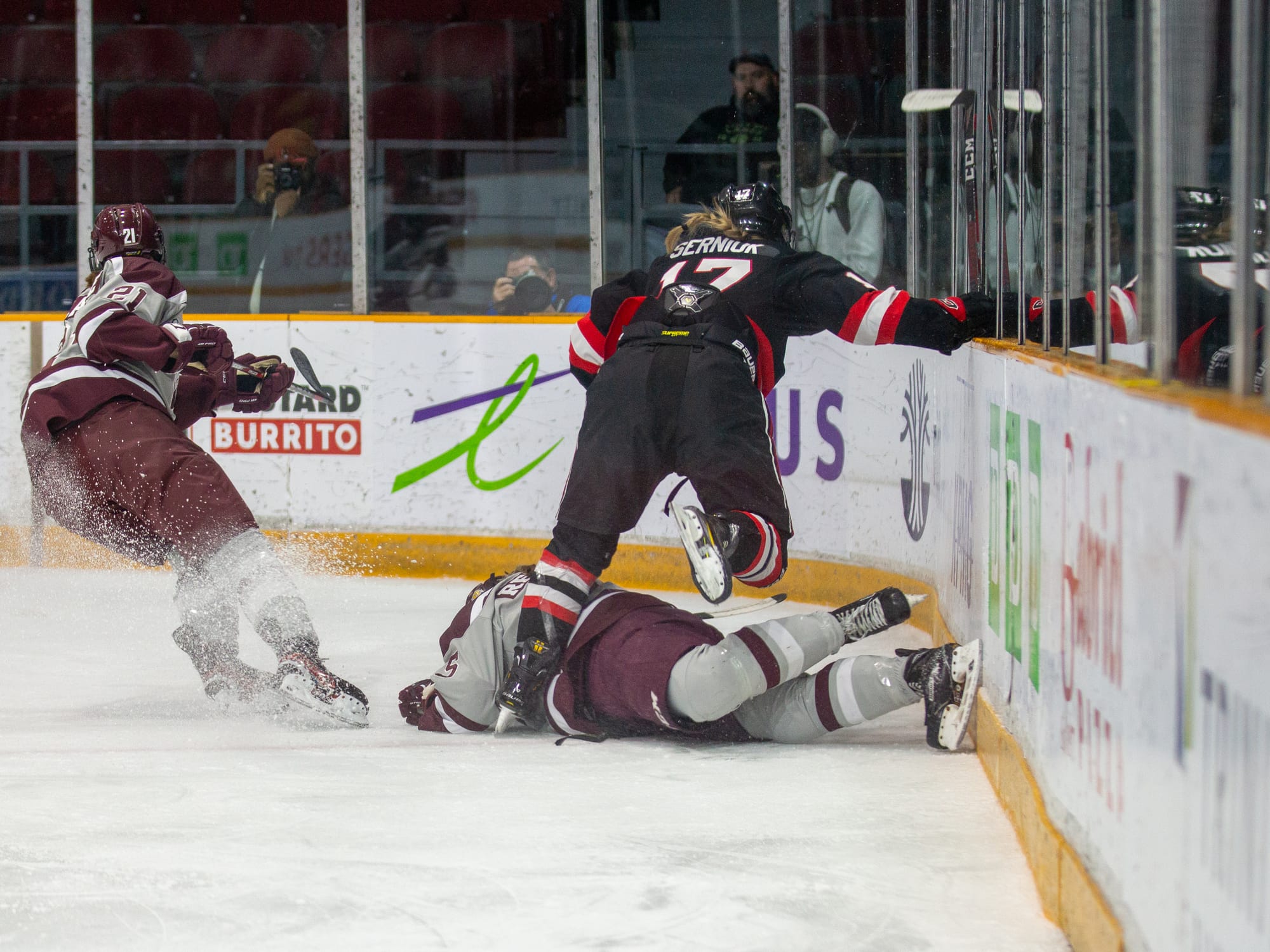 Carleton player Heyden Serniuk trips over a uOttawa player laying on the ice. 