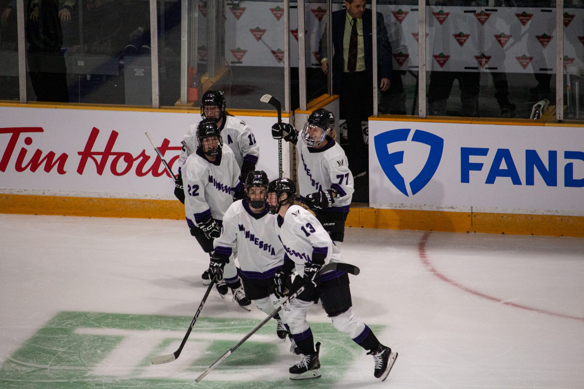 Five PWHL Minnesota players celebrate in front of the penalty box