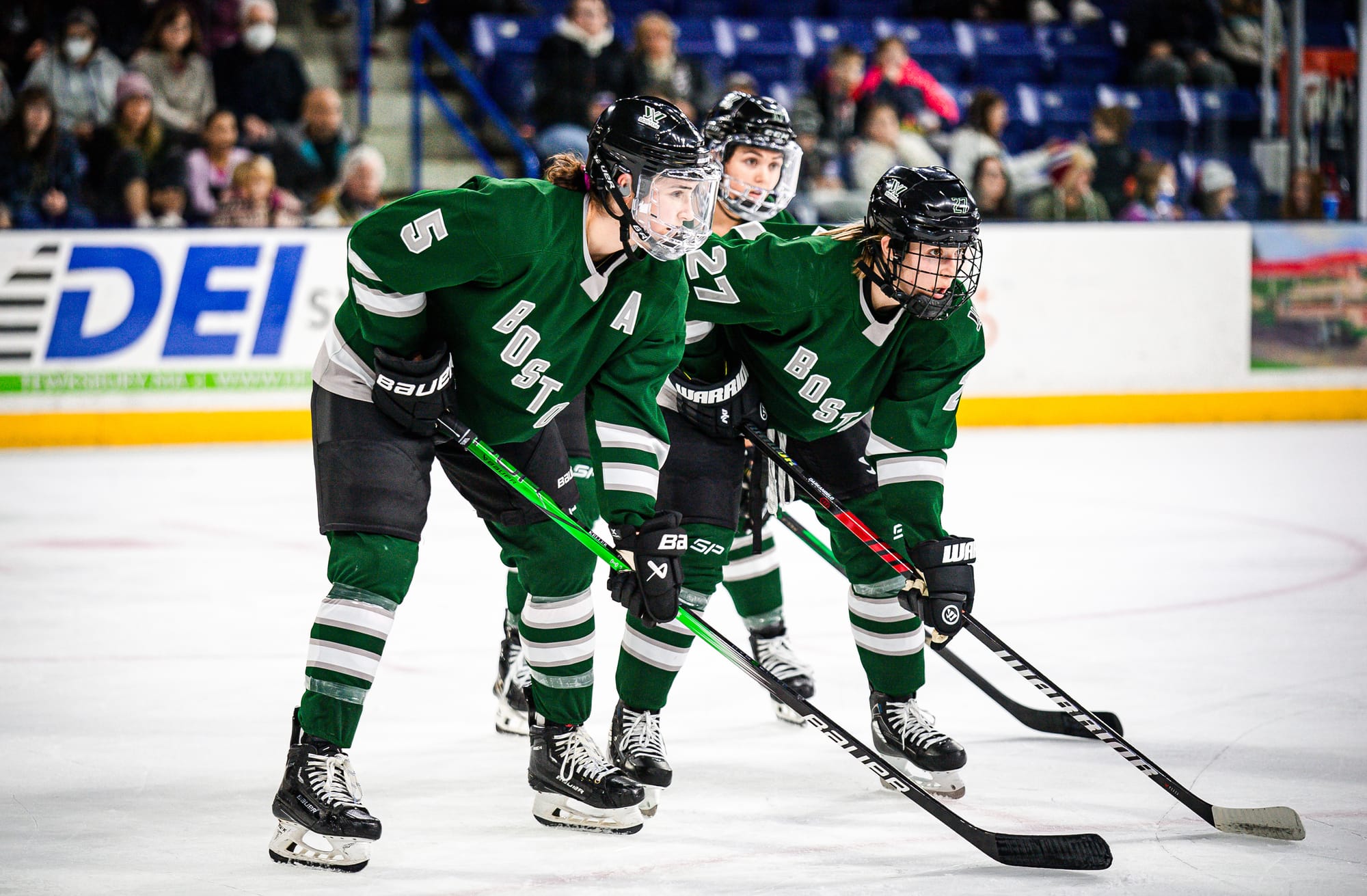 Boston players, wearing their green home uniforms, prepare for a face-off. 