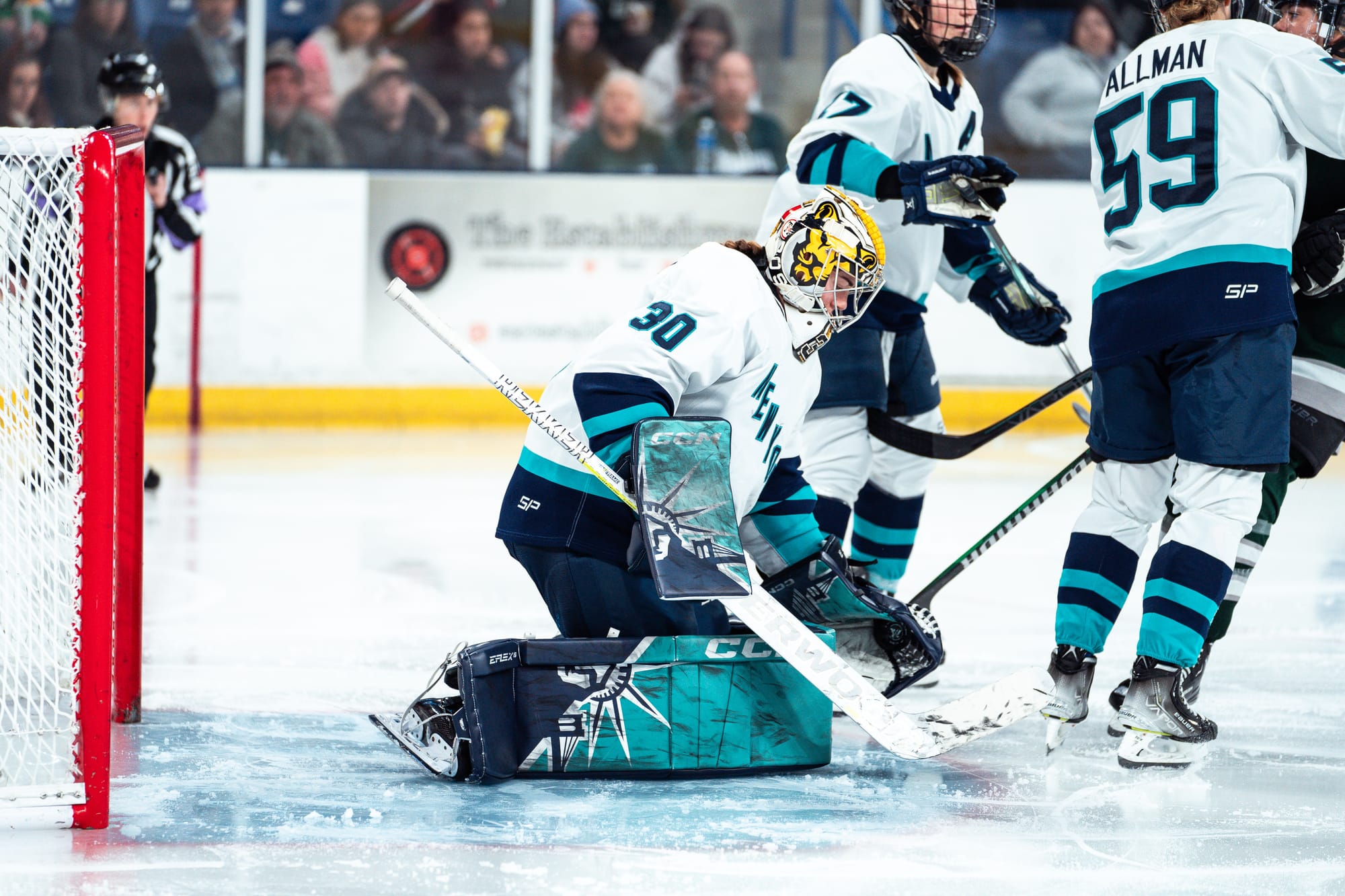 Corinne Schroeder, wearing her white away jersey, Boston Pride mask, and New York pads, makes a save against Boston.