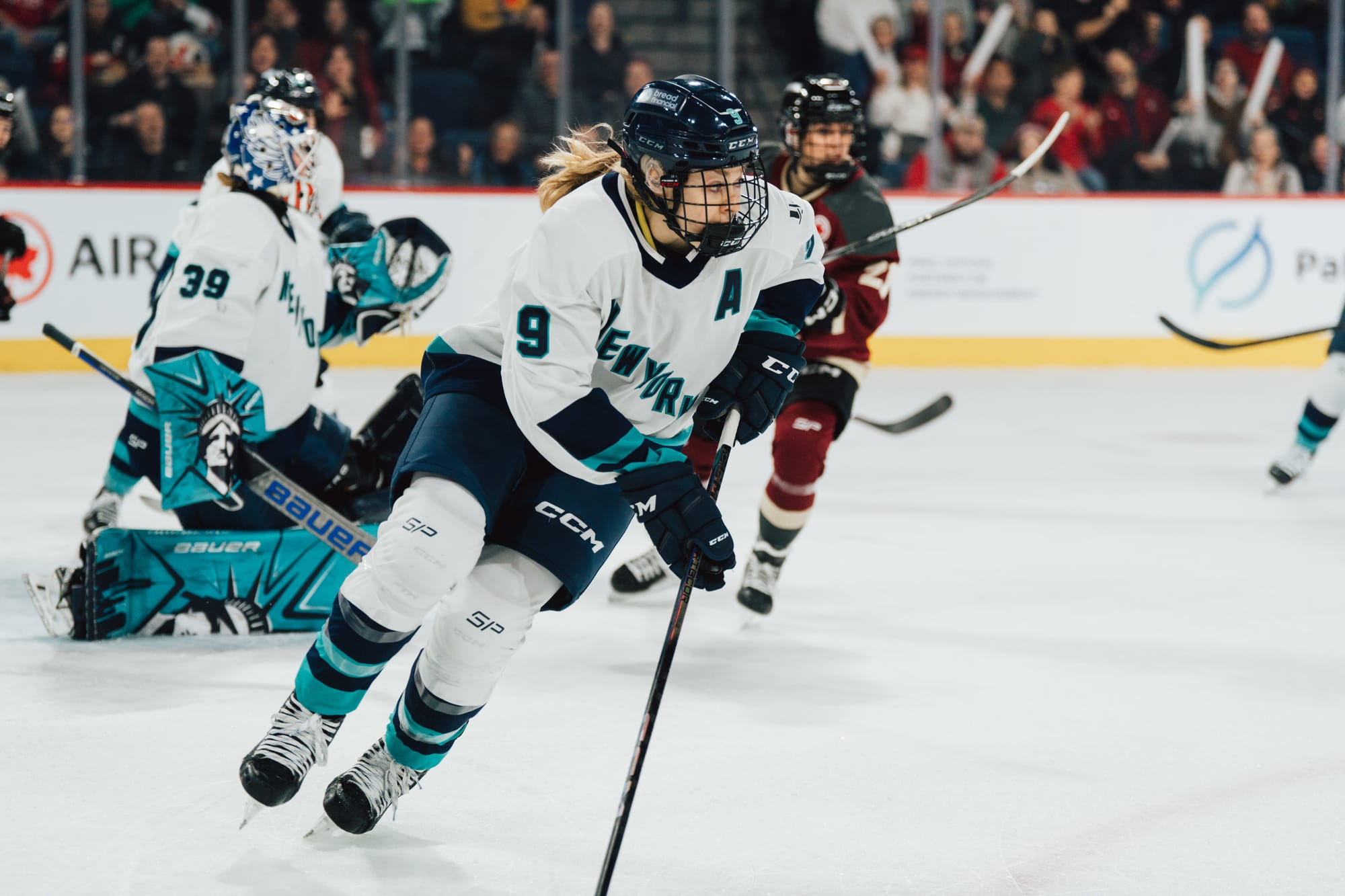 Jessie Eldridge, wearing a white away uniform, carries the puck in a game against Montréal. 