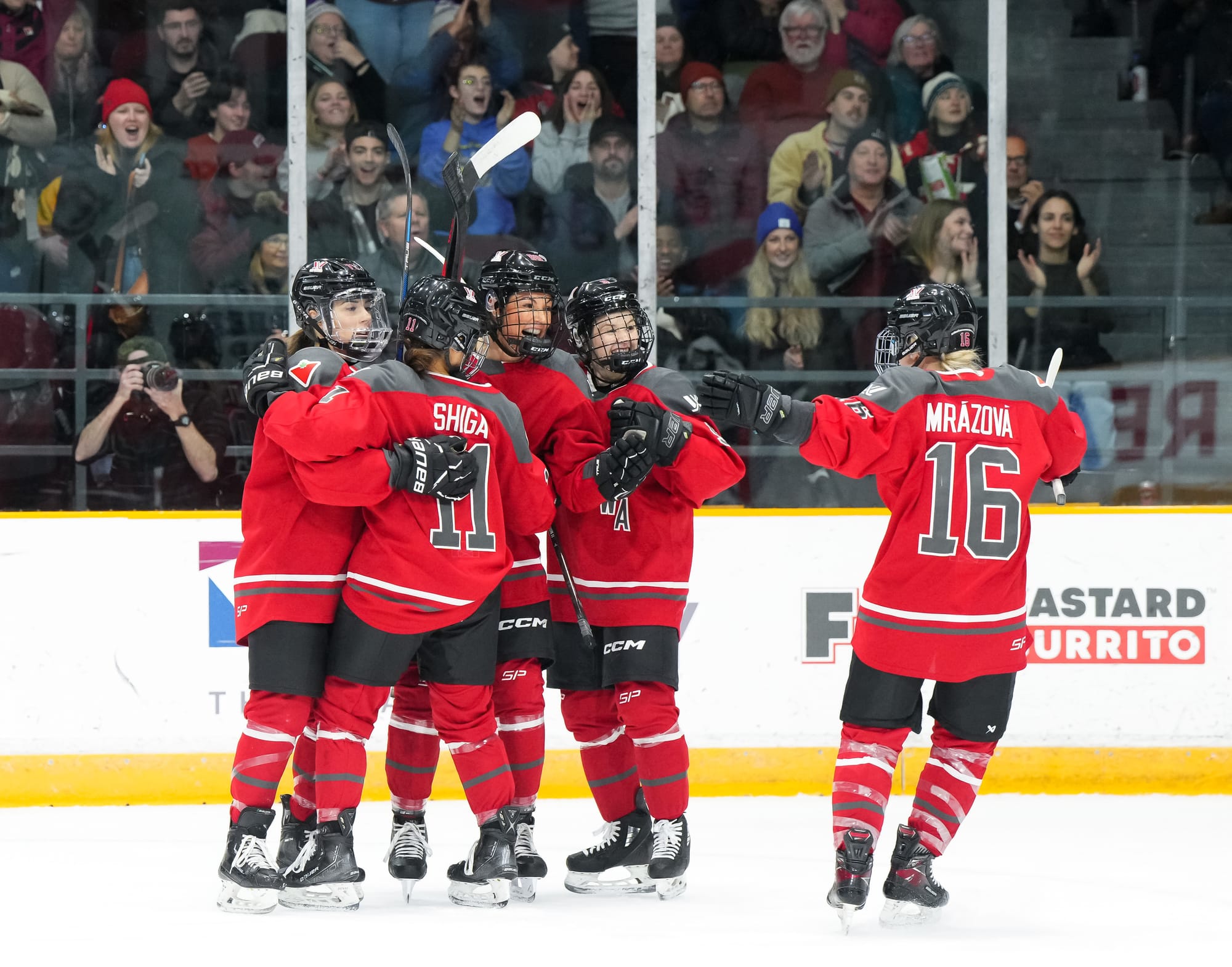 Ottawa players, wearing their red home uniforms, celebrate a goal against Minnesota. 