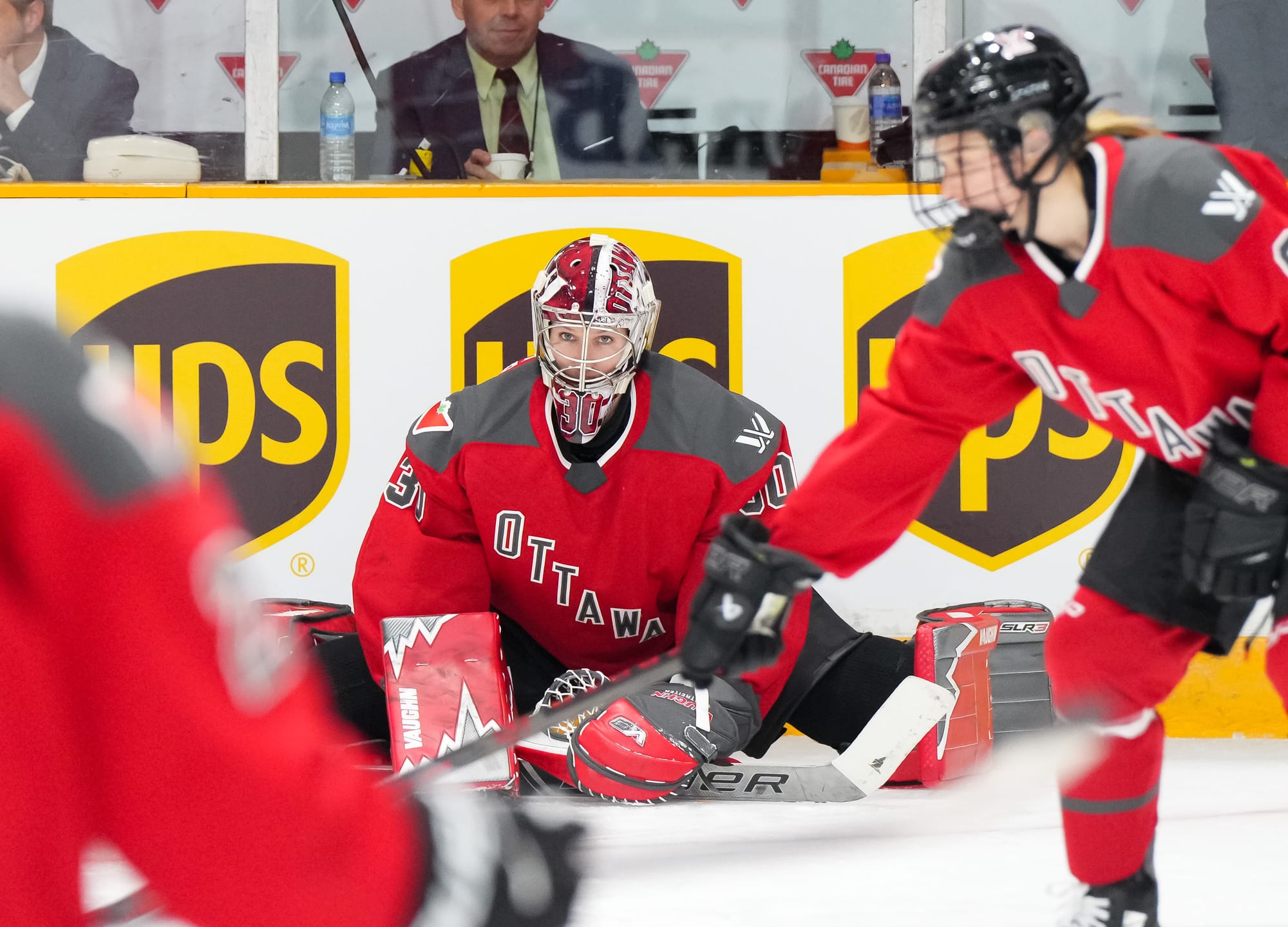 Sandra Abstreiter, wearing her Ottawa mask and pads and a red home uniform, stretches during warm-ups before a game. 