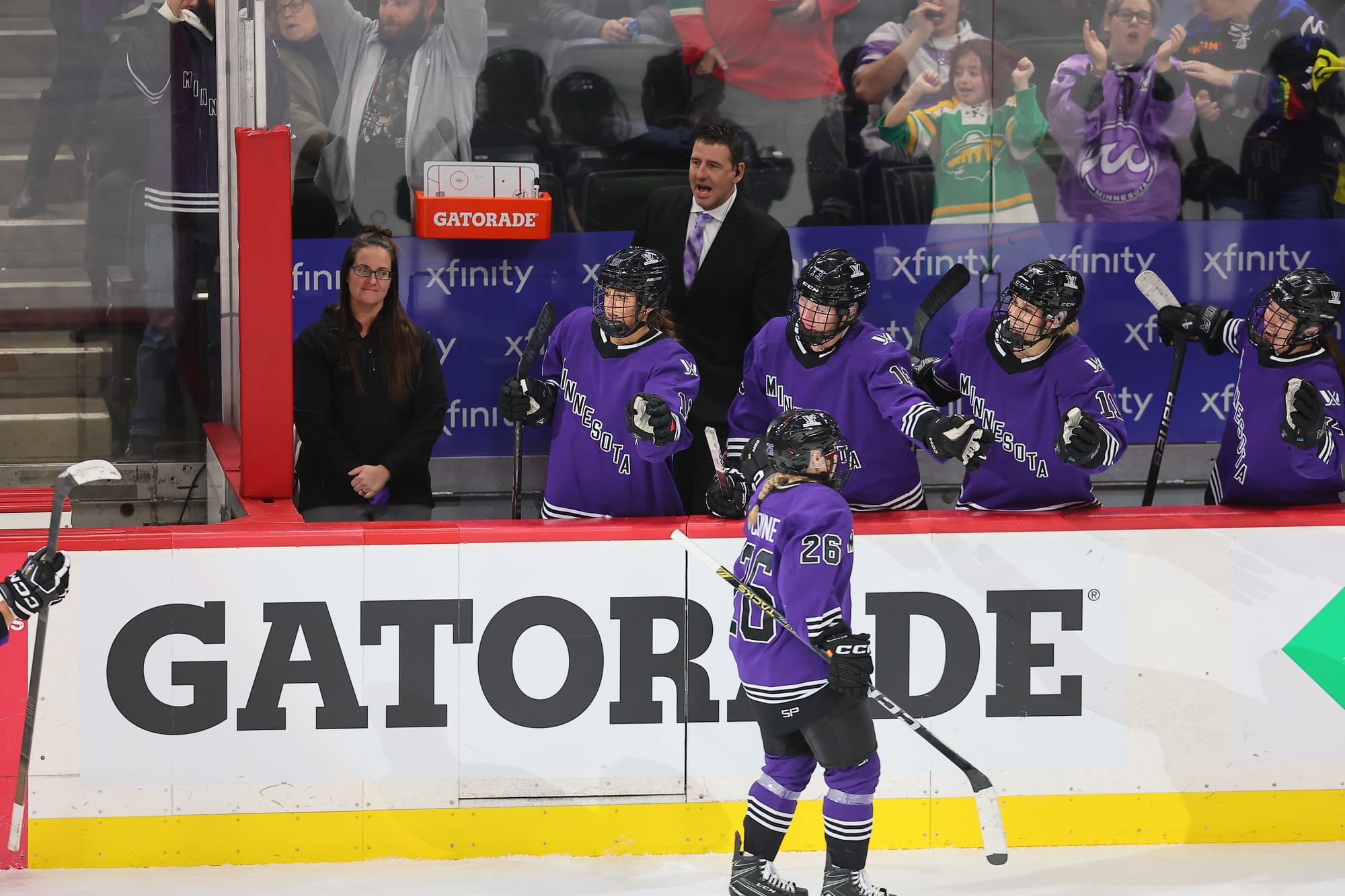 Minnesota captain Kendall Coyne Schofield, wearing a purple home uniform, celebrates at the bench after her first PWHL goal.