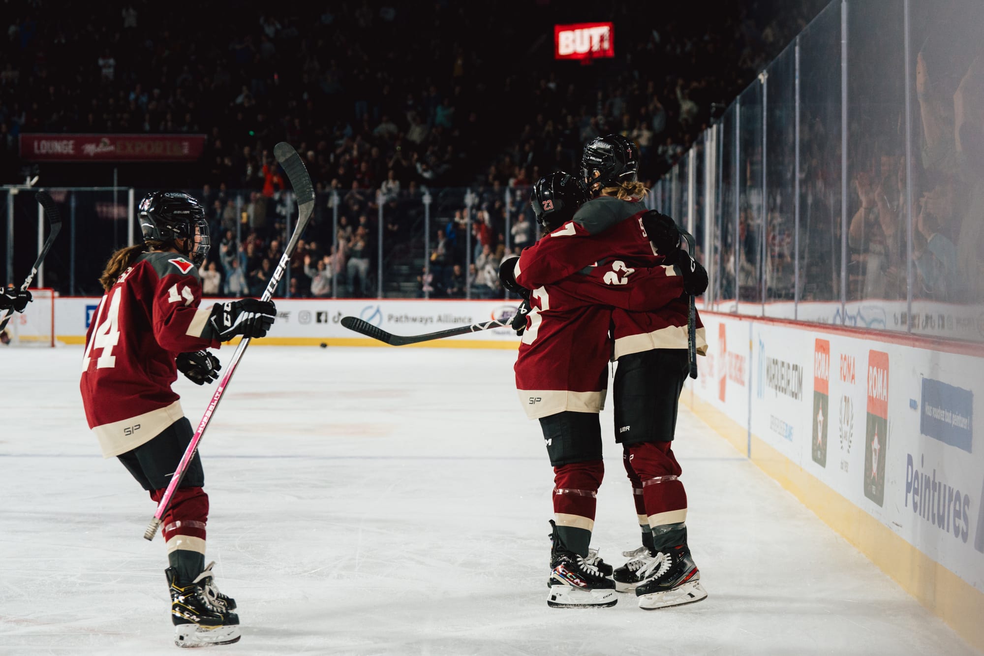 Laure Stacey celebrates her goal against Ottawa with her teammates, all wearing their maroon home uniforms..