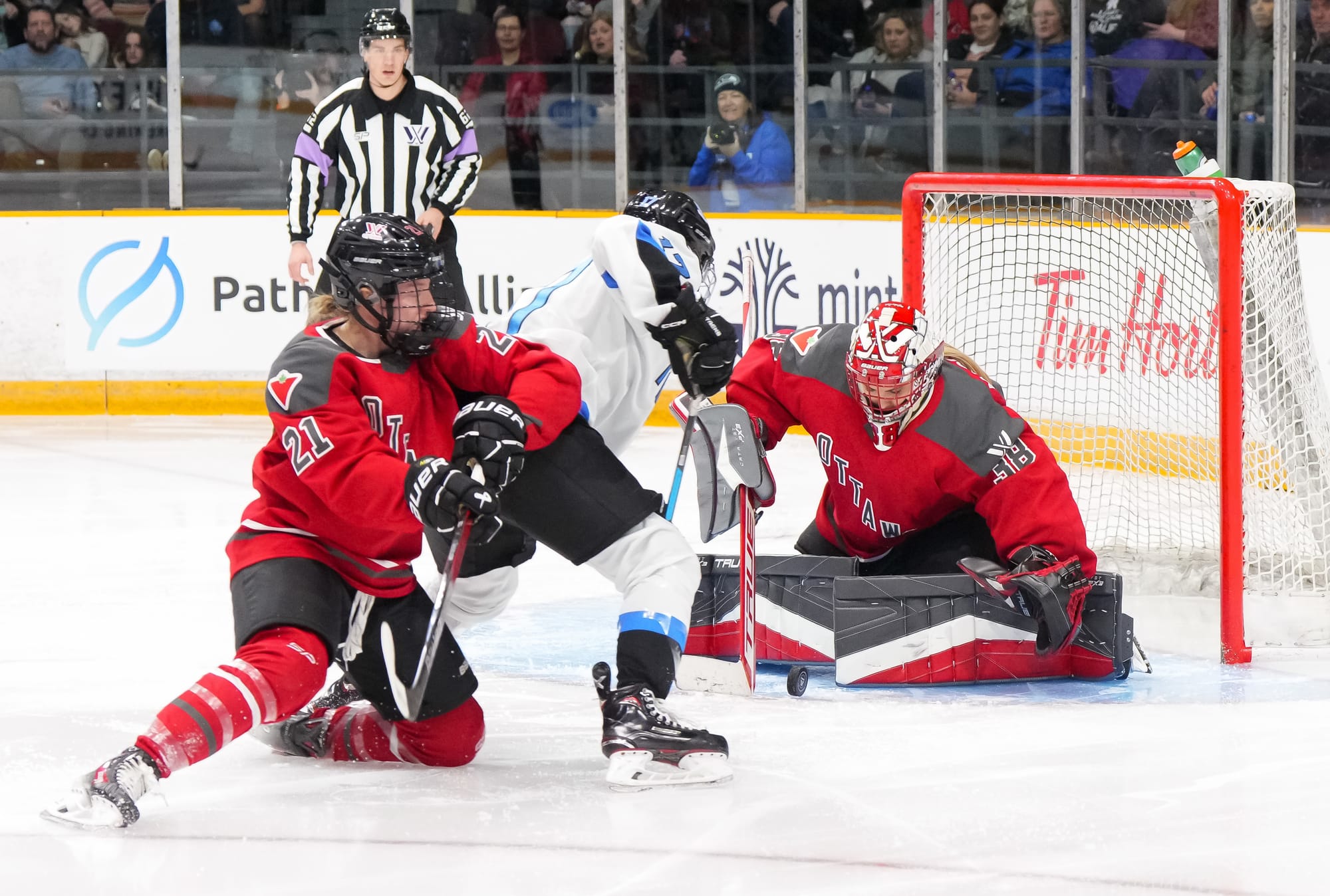 Wearing their red home uniforms, Emerance Maschmeyer makes a save as Ashton Bell tries to defend against a Toronto player.