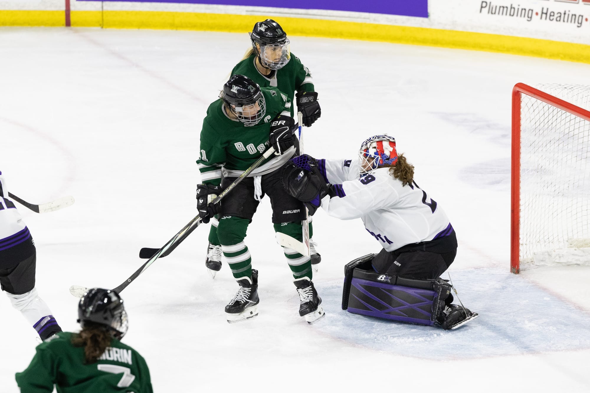 Nicole Hensley, in her white away jersey and Minnesota pads, pushes Hilary Knight, wearing her green home uniform, out of her crease.