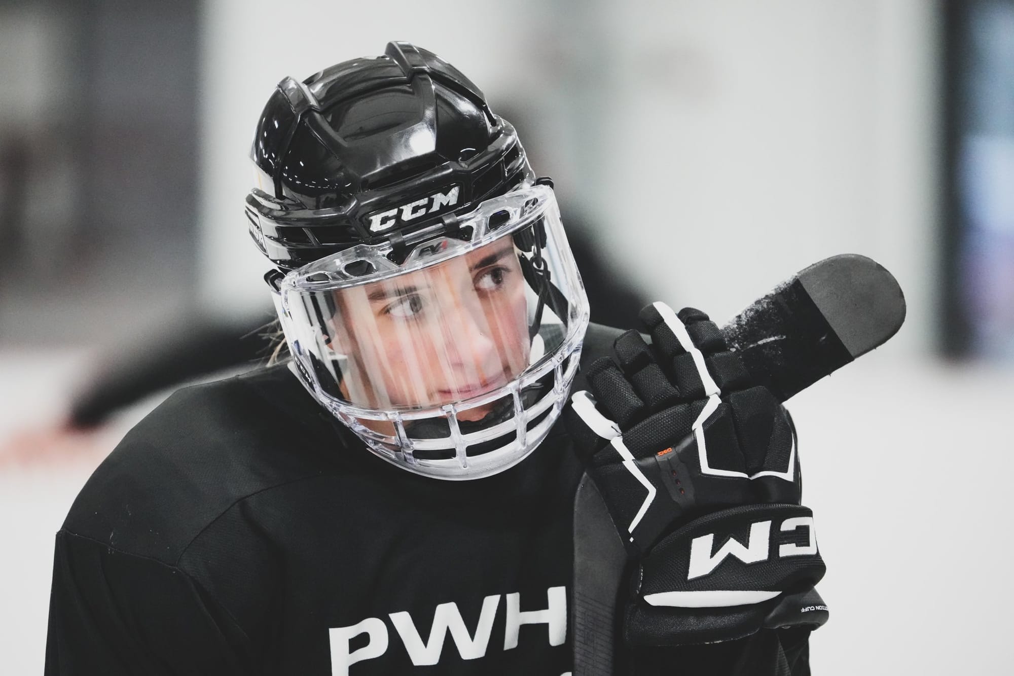 Close up of Hayley Scamurra on the ice in a black PWHL practice jersey. She is holding the blade of her stick in her hand.