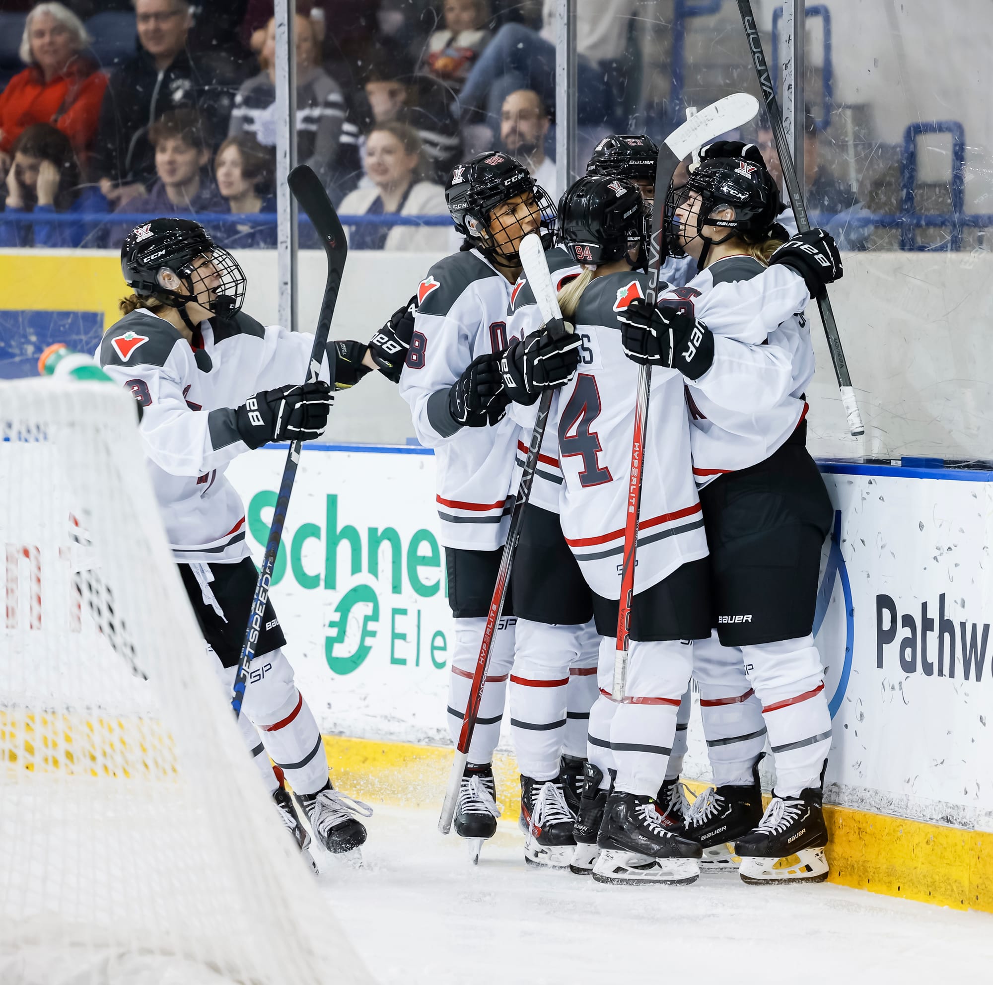 Members of PWHL Ottawa, wearing their white away uniforms, celebrate a goal against Toronto.