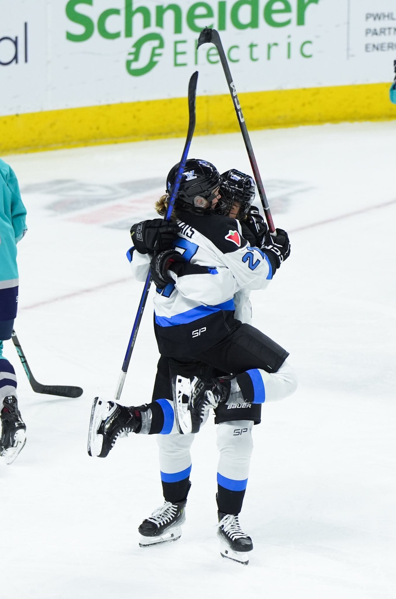 Emma Maltais celebrates her game-winning goal with a teammate in their white away uniforms.