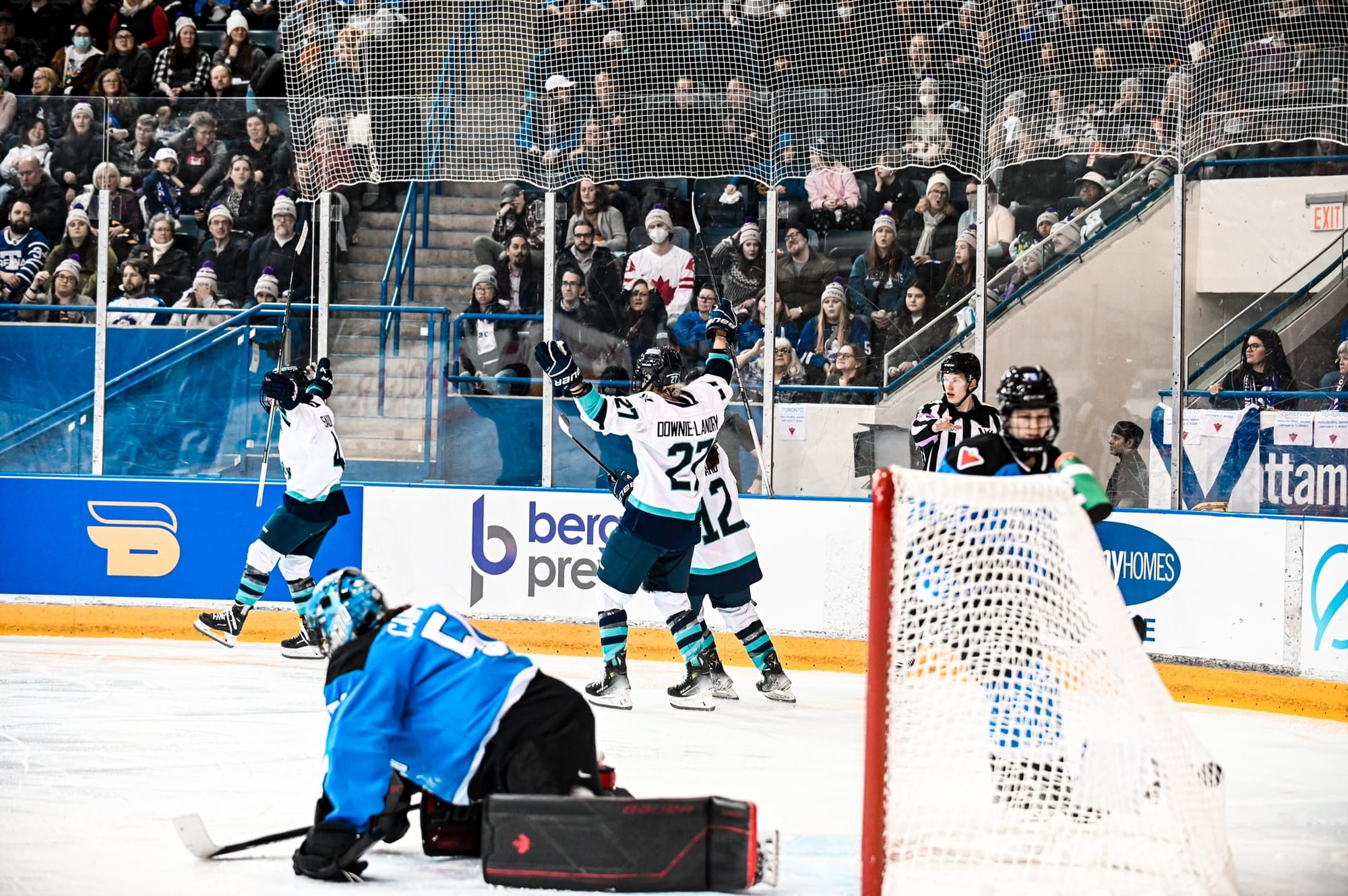 Members of PWHL New York celebrate a goal in their white away uniforms.