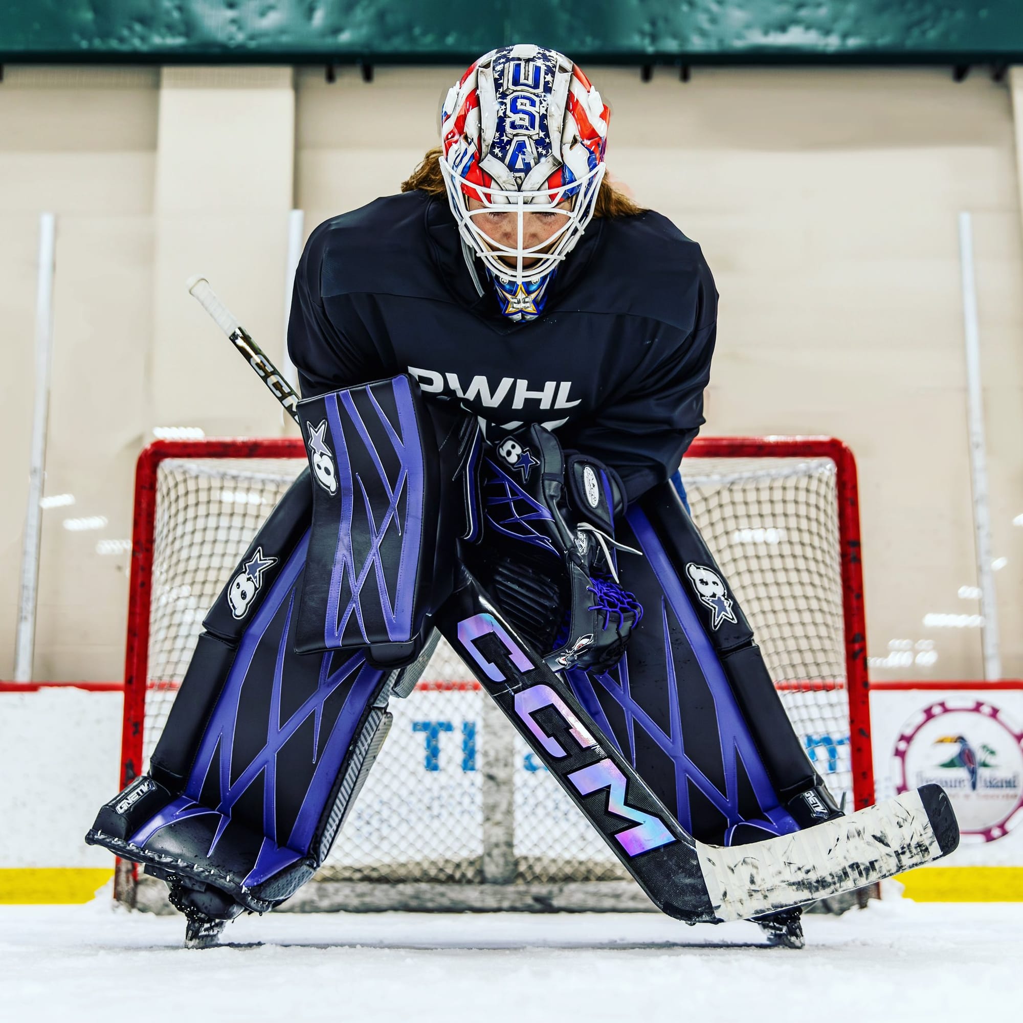Nicole Hensley. in her USA mask and new PWHL Minnesota gear, leaning over in front of her net during a practice. 