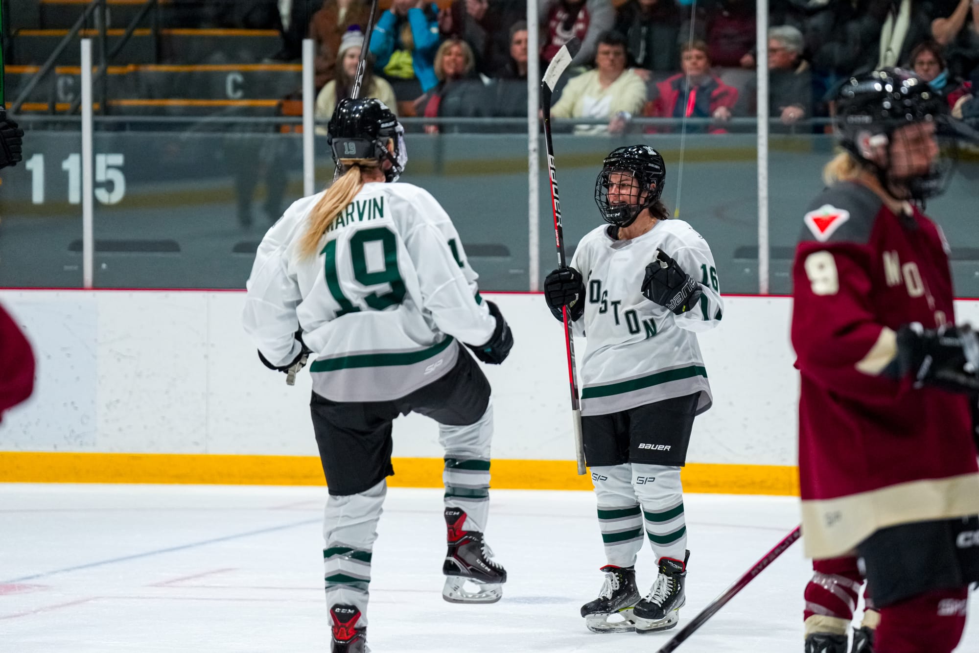 Amanda Pelkey, wearing a white away uniform, celebrates her overtime game-winner with Gigi Marvin. 