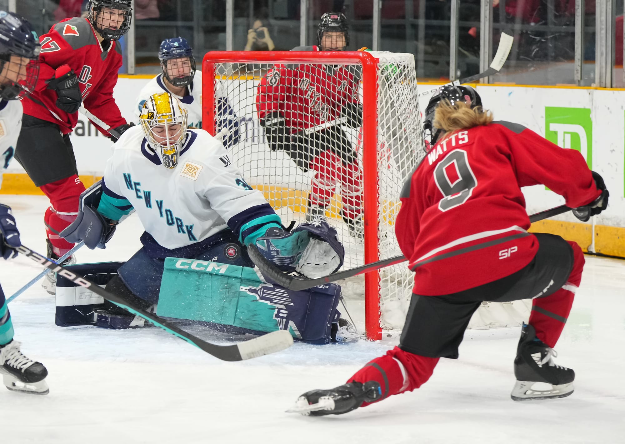 Corinne Schroeder, in the same gear described in the picture above, makes a save against Daryl Watts, who is wearing her red home uniform.