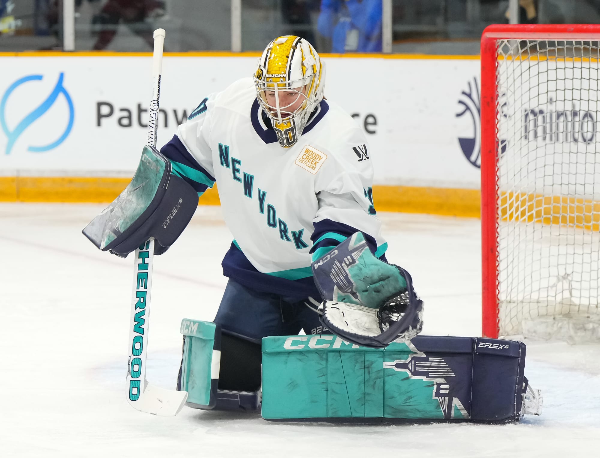 Corinne Schroeder, wearing her white away uniform, Boston Pride mask, and New York pads, makes a save during a game against Ottawa.