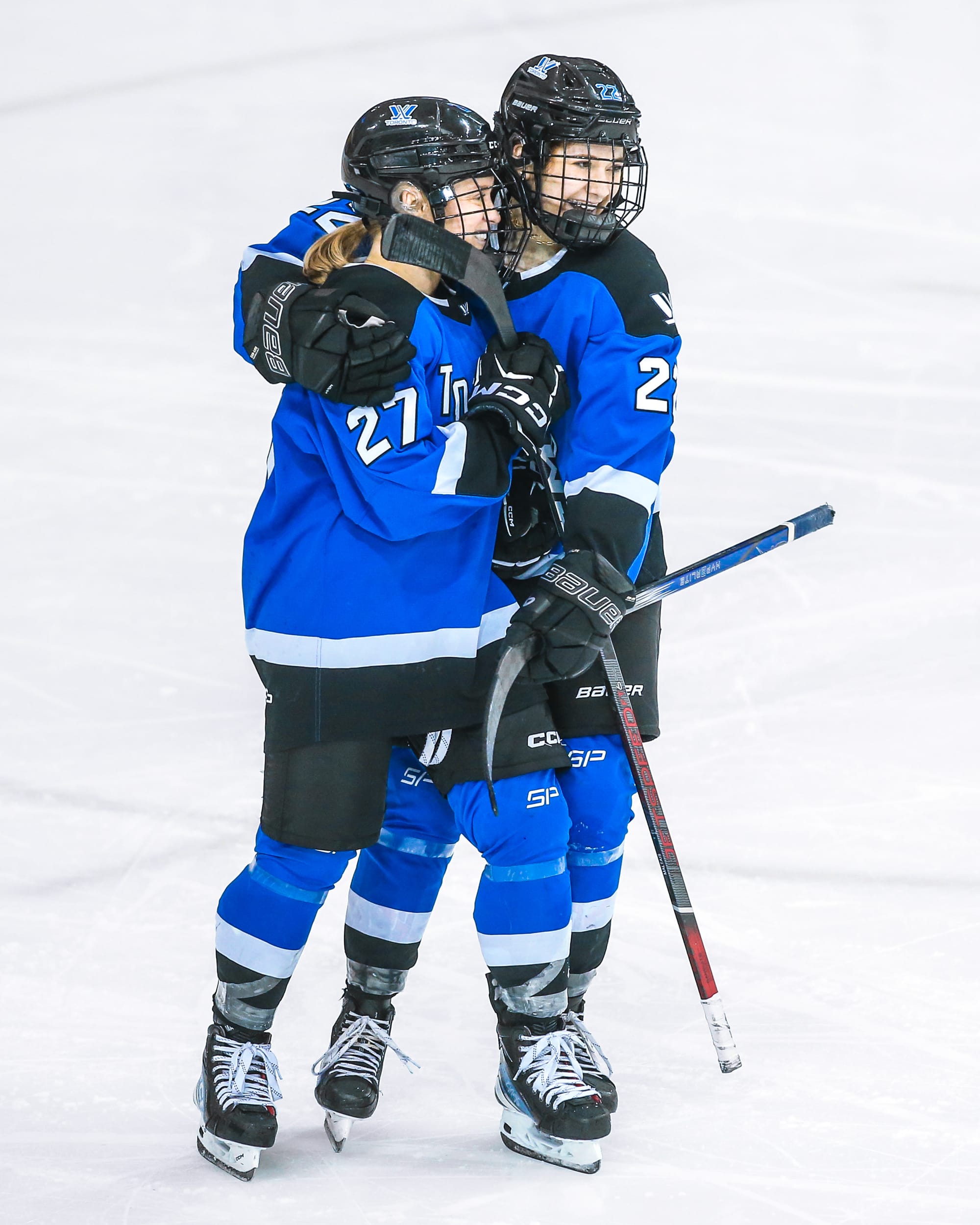 Maggie Connors embraces Emma Maltais. Both are wearing their blue home uniforms.