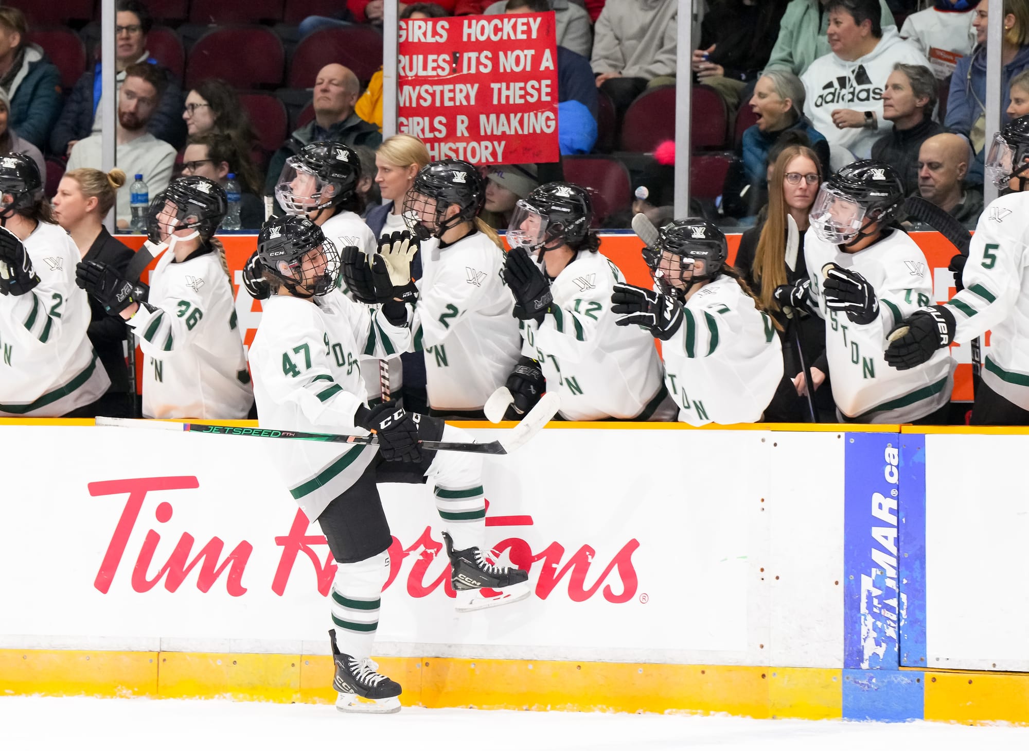 Jamie Lee Rattray celebrates her goal at the Boston bench. All the players are in their white Boston away uniforms.