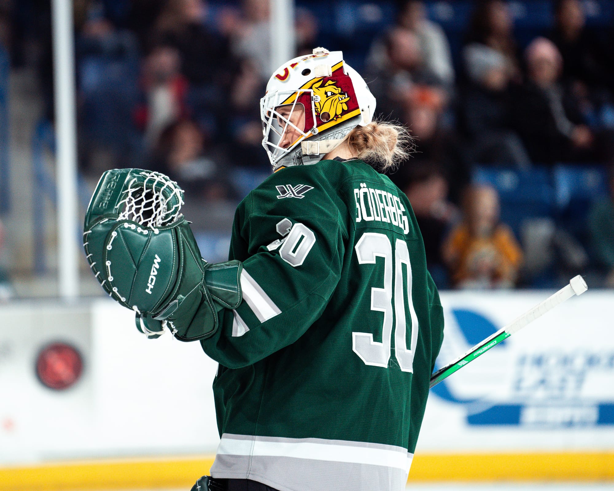 Emma Söderberg celebrates Boston's win over Minnesota. She is wearing her green home uniform and green Boston pads, with her maroon/gold/white University of Minnesota-Duluth mask.