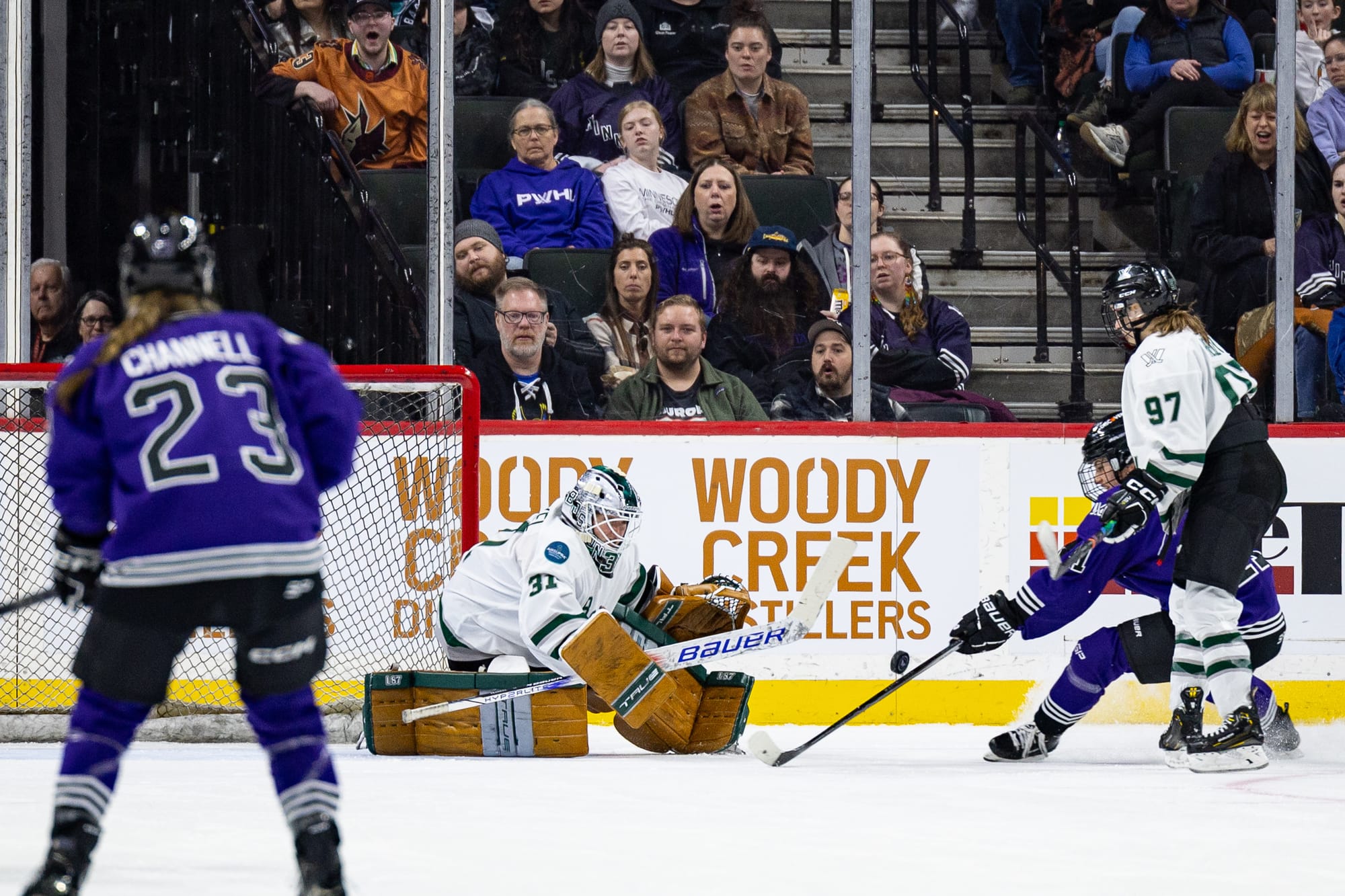 Aerin Frankel makes a save against Minnesota. She is wearing her white jersey, Boston mask, and brown pads.