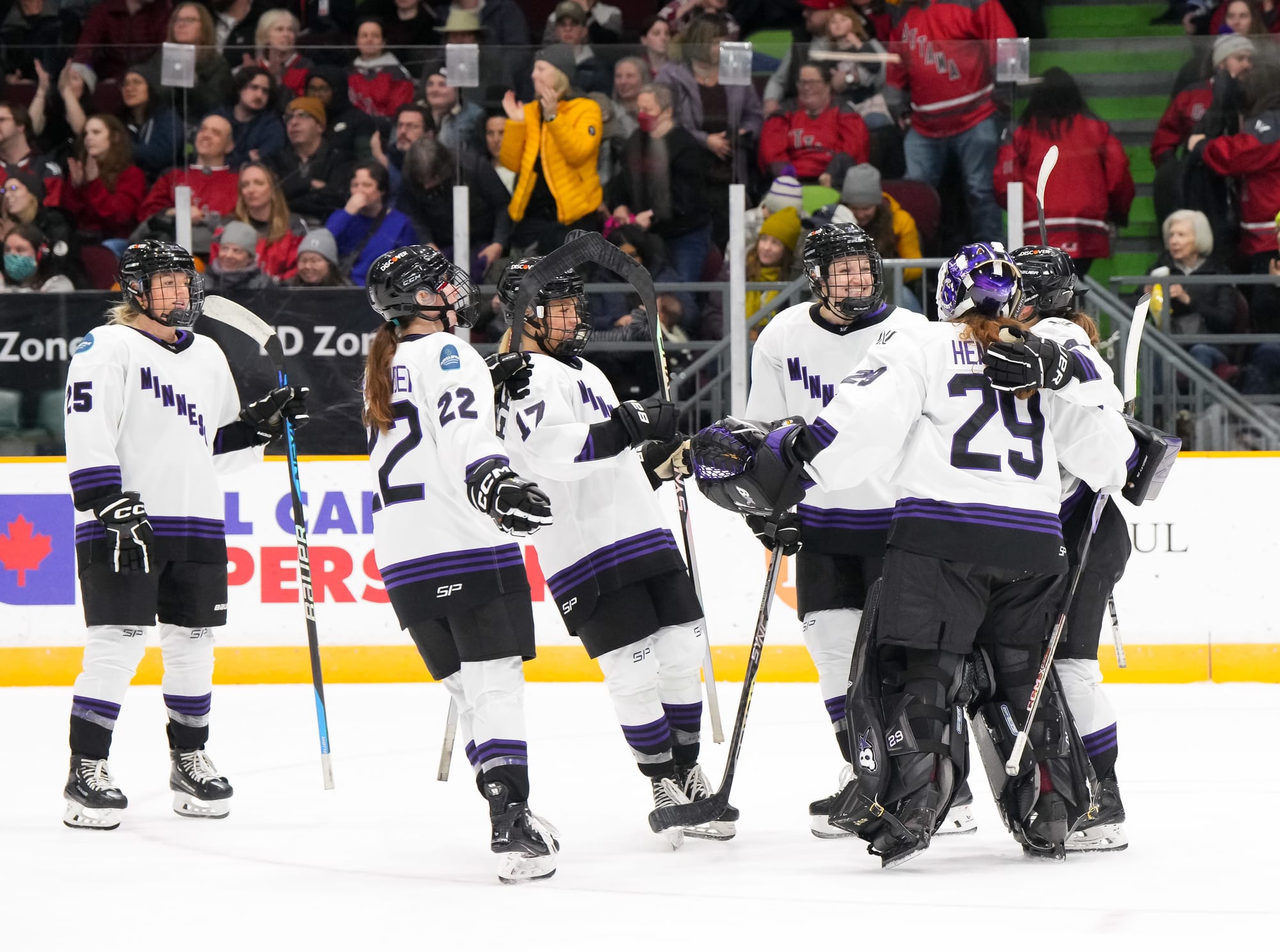 Minnesota players, wearing their white home jerseys, celebrate their win over Ottawa with goaltender Nicole Hensley.