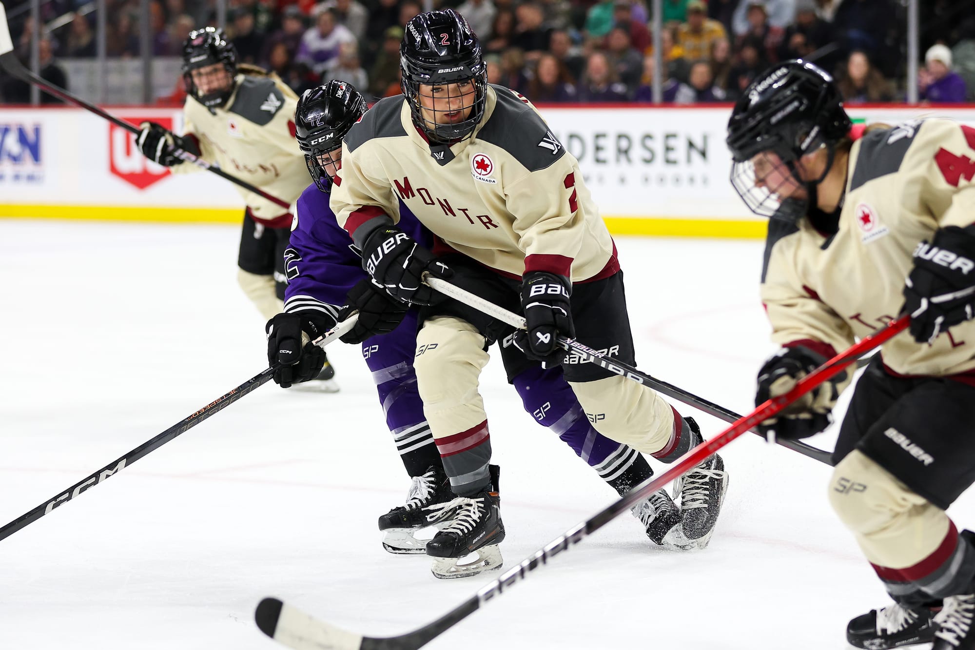 Keopple provides support by blocking a Minnesota defender as Boulier skates with the puck. Both Montréal players are in cream away uniforms.