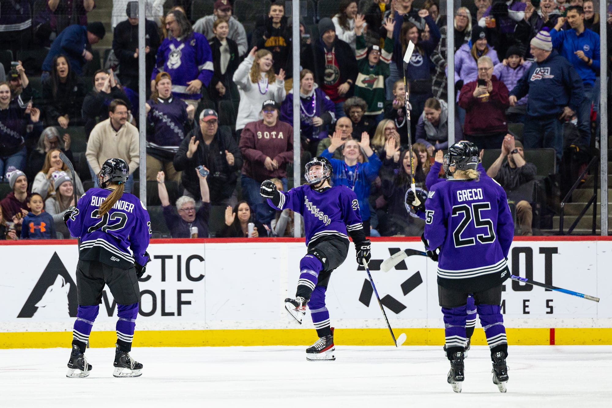 Abbey Boreen celebrates her goal against Ottawa. She has one leg in the air as she points at Natalie Buchbinder while Emma Greco looks on. All players are wearing purple home jerseys.