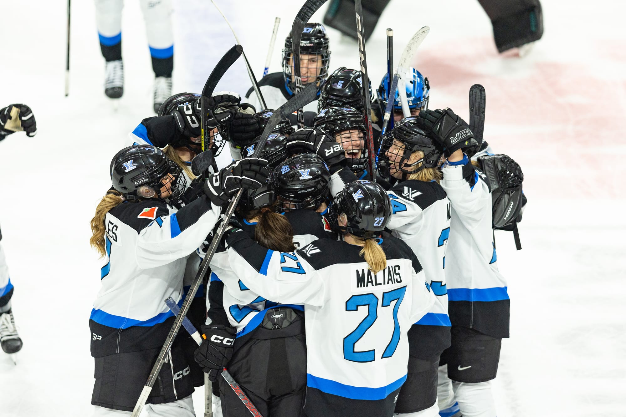 Toronto players celebrate their win against Minnesota. They are in a massive group hug, and wearing their white away uniforms.