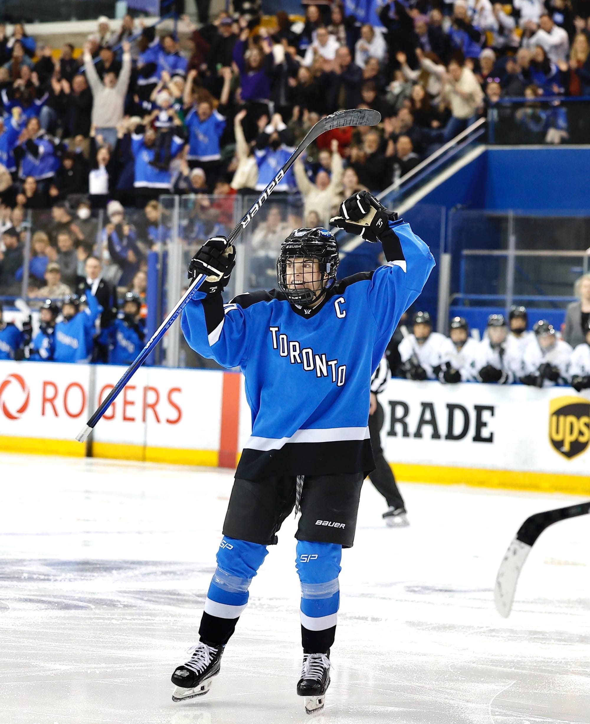 Blayre Turnbull celebrates a goal against Boston. Her arms are raised above her head in celebration. She is wearing a blue home uniform.