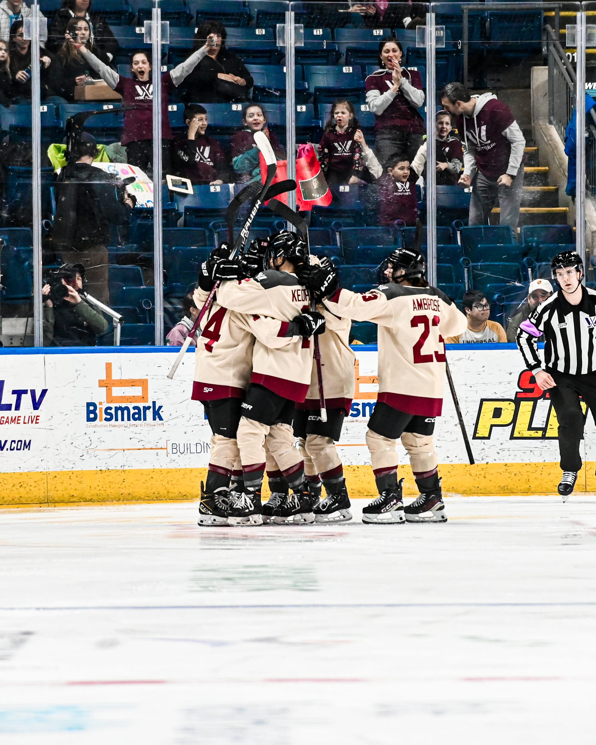 Montréal players celebrate a goal against New York. They are in a big group hug and all wearing their cream away jerseys.