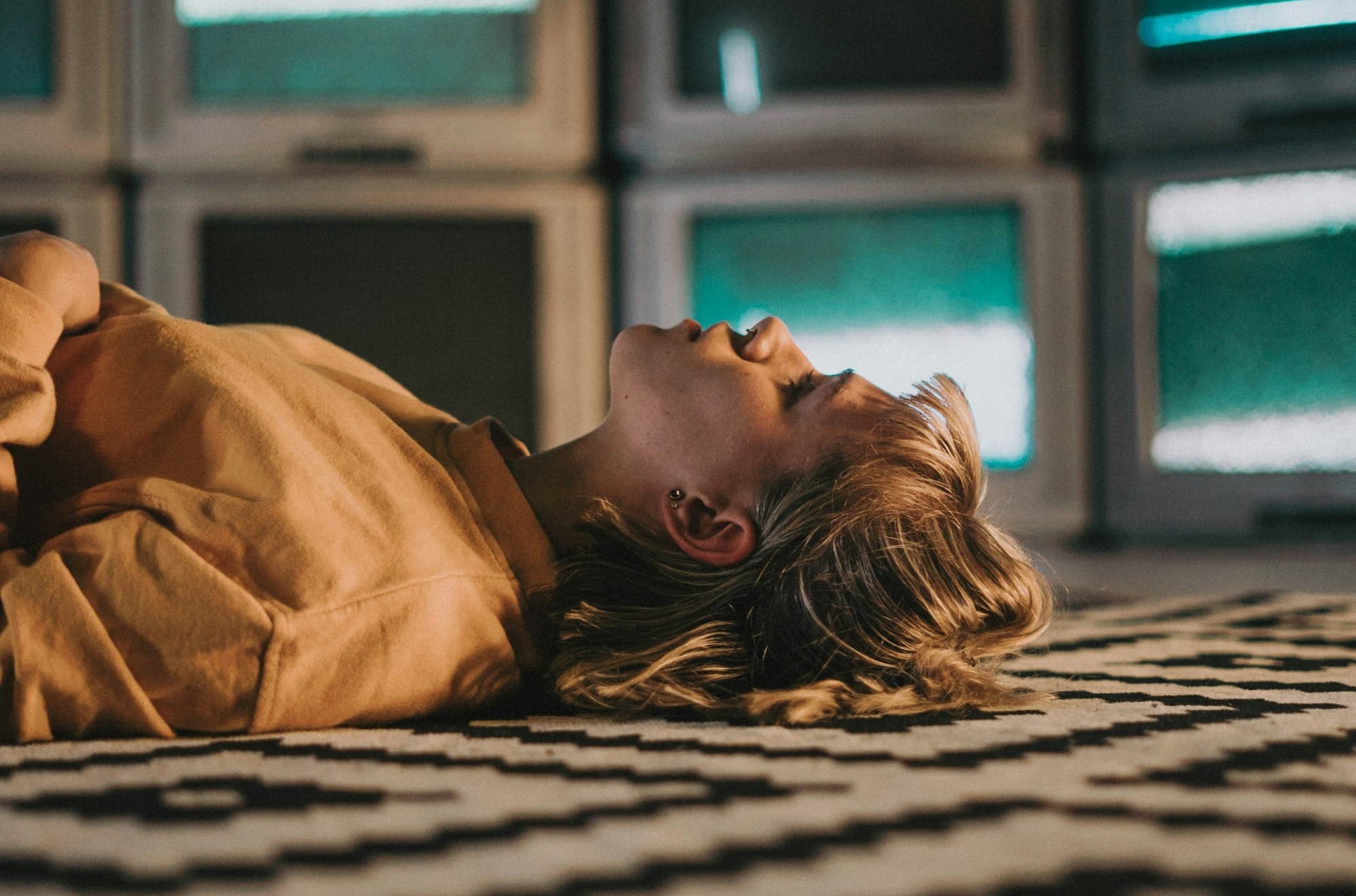 woman in brown shirt lying on black and white textile