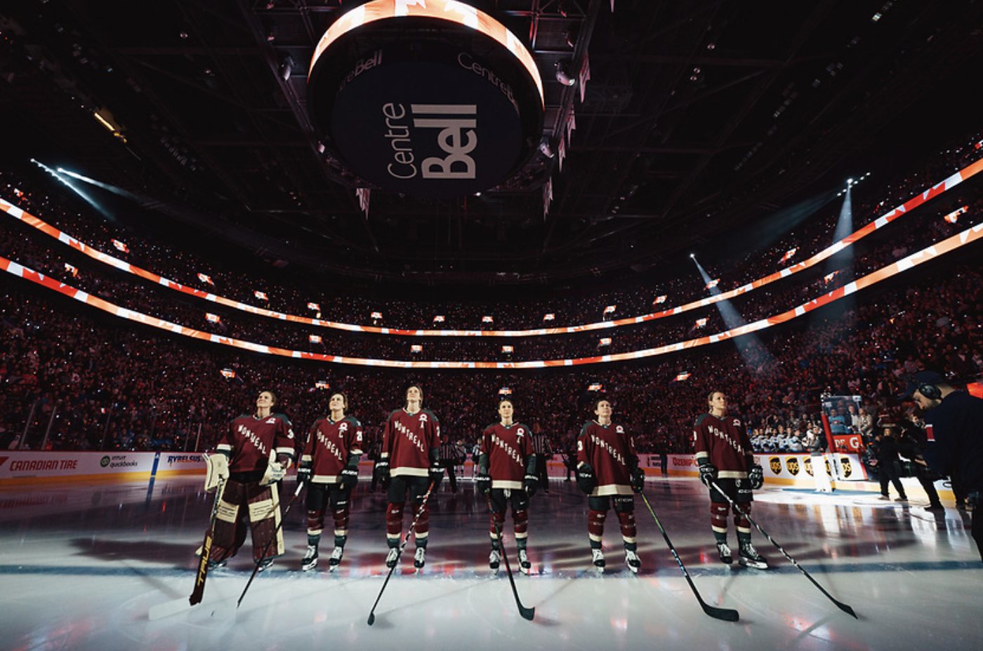 Montréal players stand on the blue line. There are five skaters and one goaltender. Their helmets are off, and they are wearing maroon home jerseys.