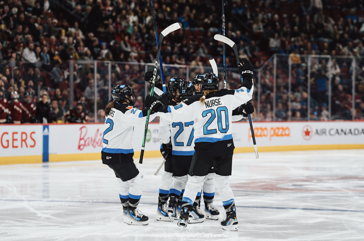 Toronto players celebrate a goal against Montréal with a big group hug at the blueline. There are five of them wearing white away jerseys.