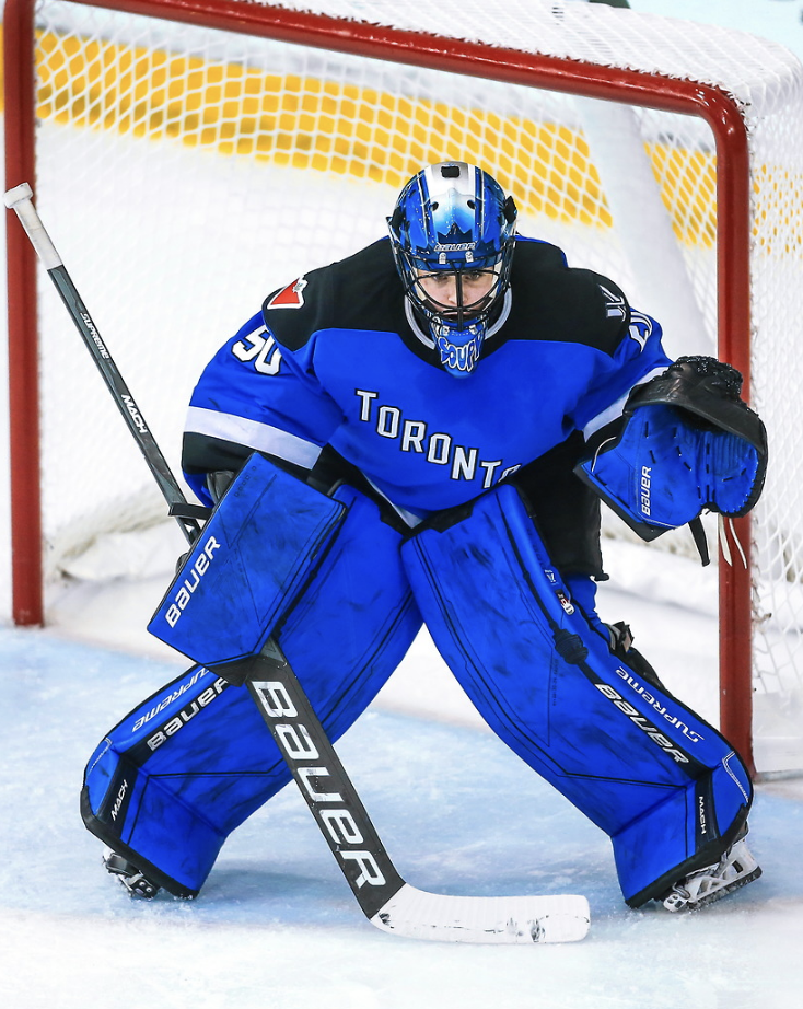  Kristen Campbell prepares to make a save. She is crouched with her stick blocking part of her five-hole and glove slightly raised. She is in a blue home uniform and her all-blue Toronto goalie gear.