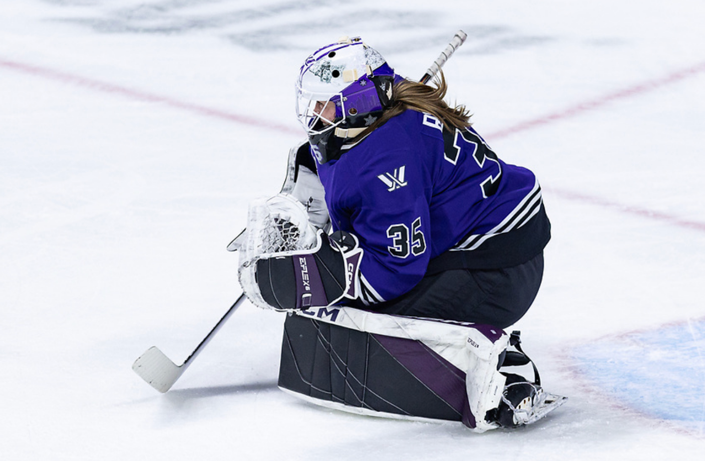 Rooney squeeze her knees together from the butterfly position to make a save. She is in her purple/black Minnesota pads and a purple home uniform.