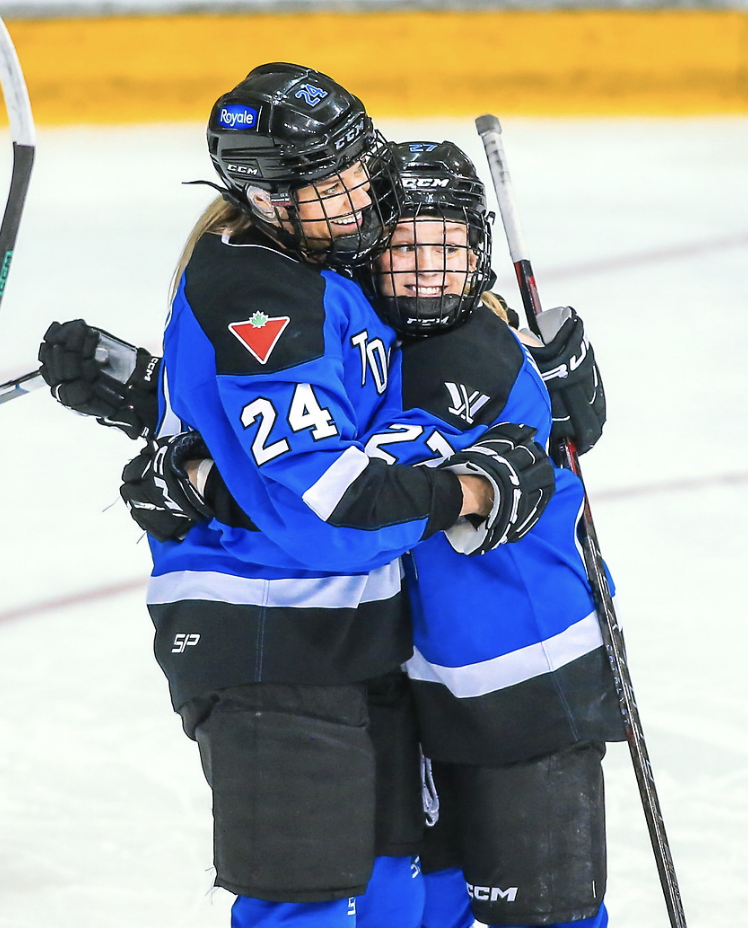 Spooner (left) and Maltais (right) smile and embrace. Both are wearing blue home uniforms.