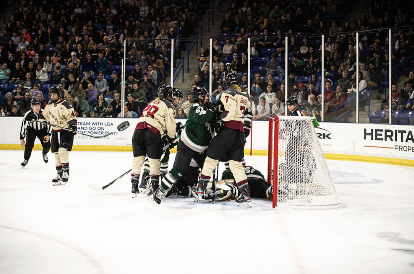 Boston and Montréal players battle in front of the Boston net. Rattray is shoving Stacey as other look on. The Montréal players are in cream away jerseys, while Boston is in green home uniforms.