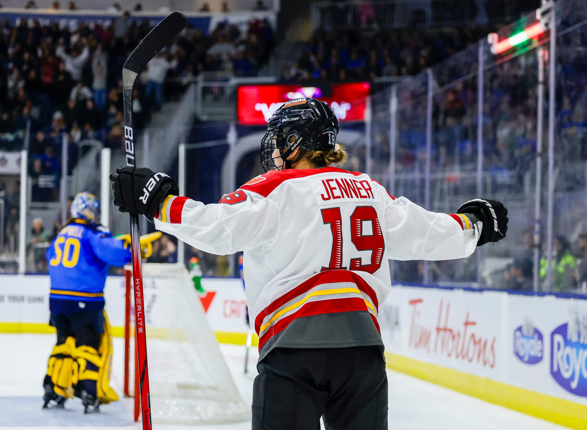 Jenner holds her arms out in expectation of a group hug after scoring against Toronto. She is wearing a white away uniform.