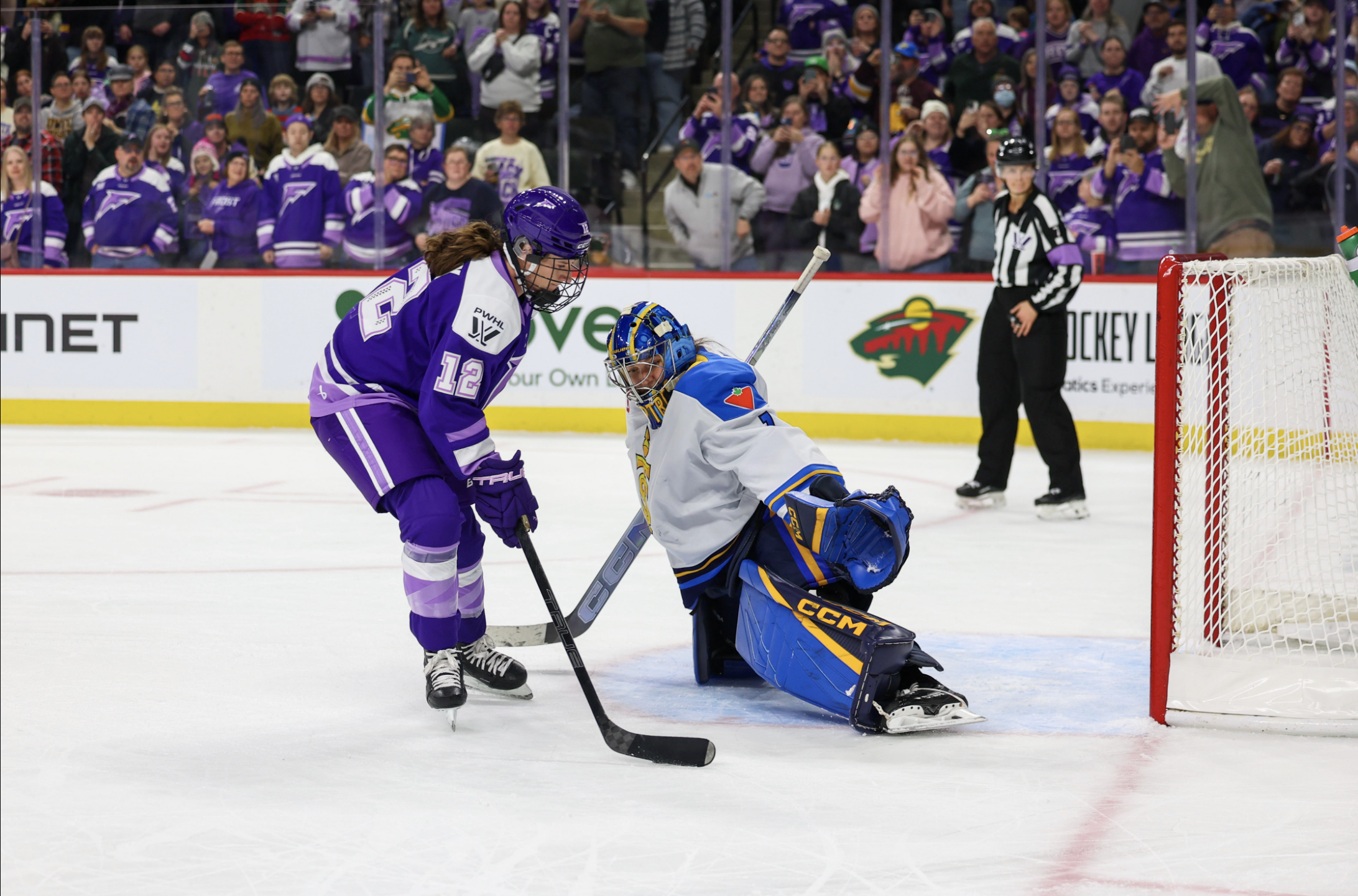 Pannek makes a move outside of Raygan Kirk's crease to try to score. Pannek is wearing a purple home uniform, while Kirk is wearing a white away one.