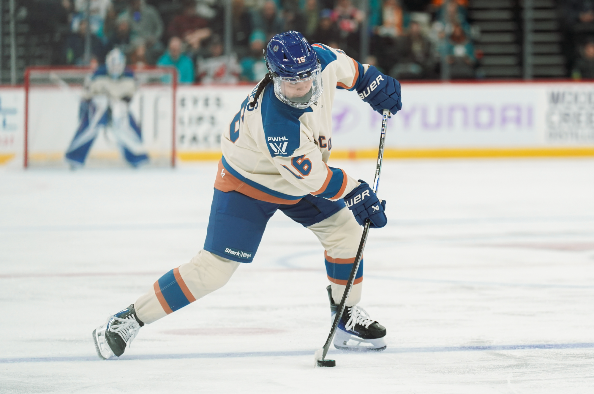 From the blueline, Jaques flexes her stick as she prepares to fire a shot towards the net. She is wearing a cream away uniform.