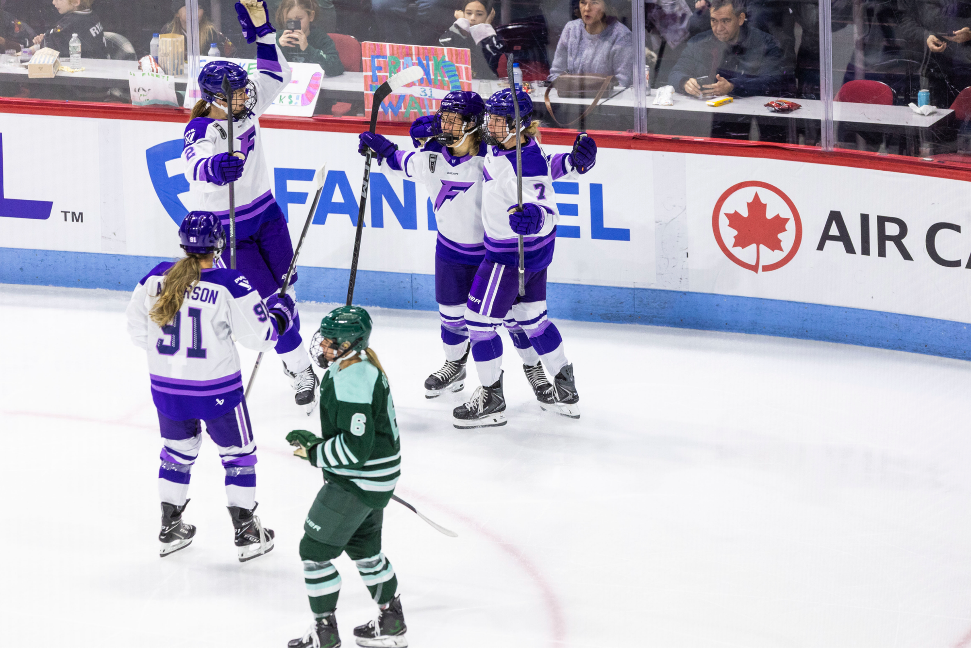 Minnesota players celebrate their goal with a group hug. They are wearing white away uniforms.