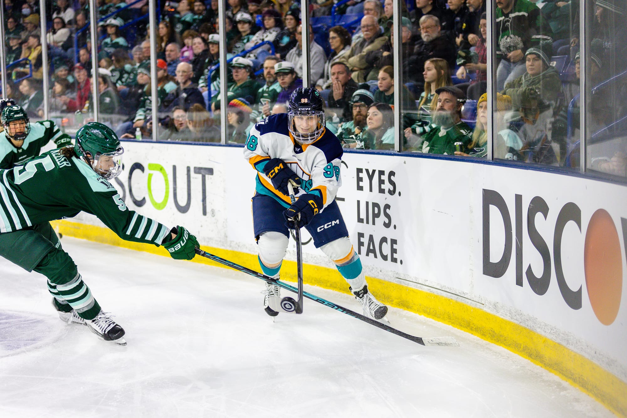 Kaltounková skates into the corner with the puck during a game against Boston. She is wearing a white away uniform.