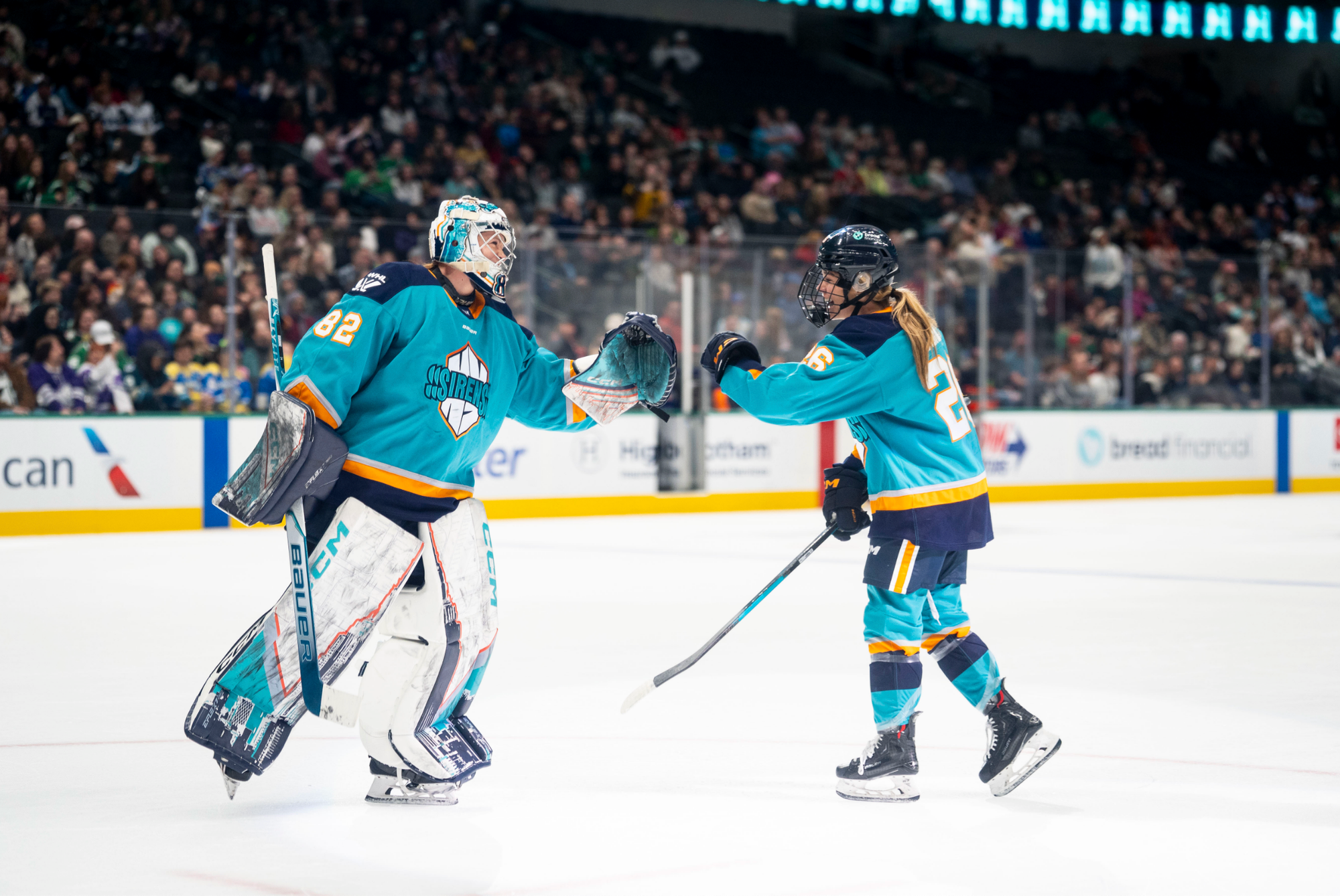 Osborne (left) smiles and reaches out to fist bump O'Brien (right), who is doing the same. They are both wearing teal away uniforms.