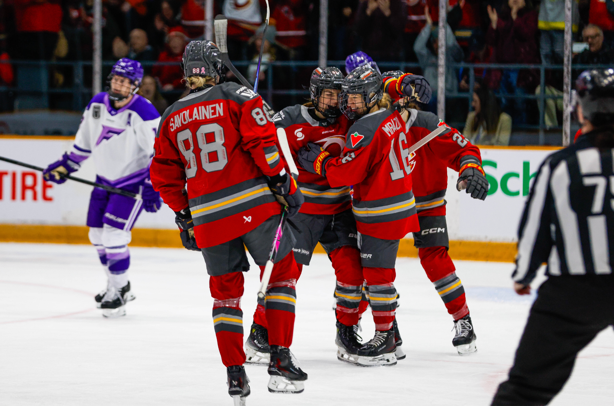 Charge players come together to celebrate a goal with a group hug. They are wearing red home uniforms.