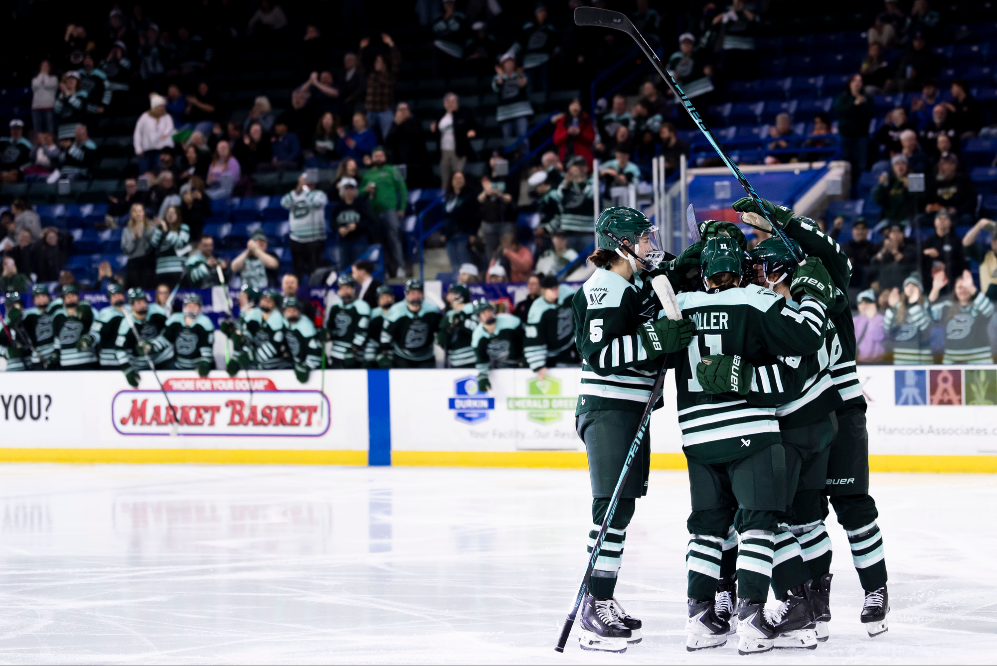 The Fleet celebrate Müller’s goal with a tight group hug. They are all wearing green home uniforms.
