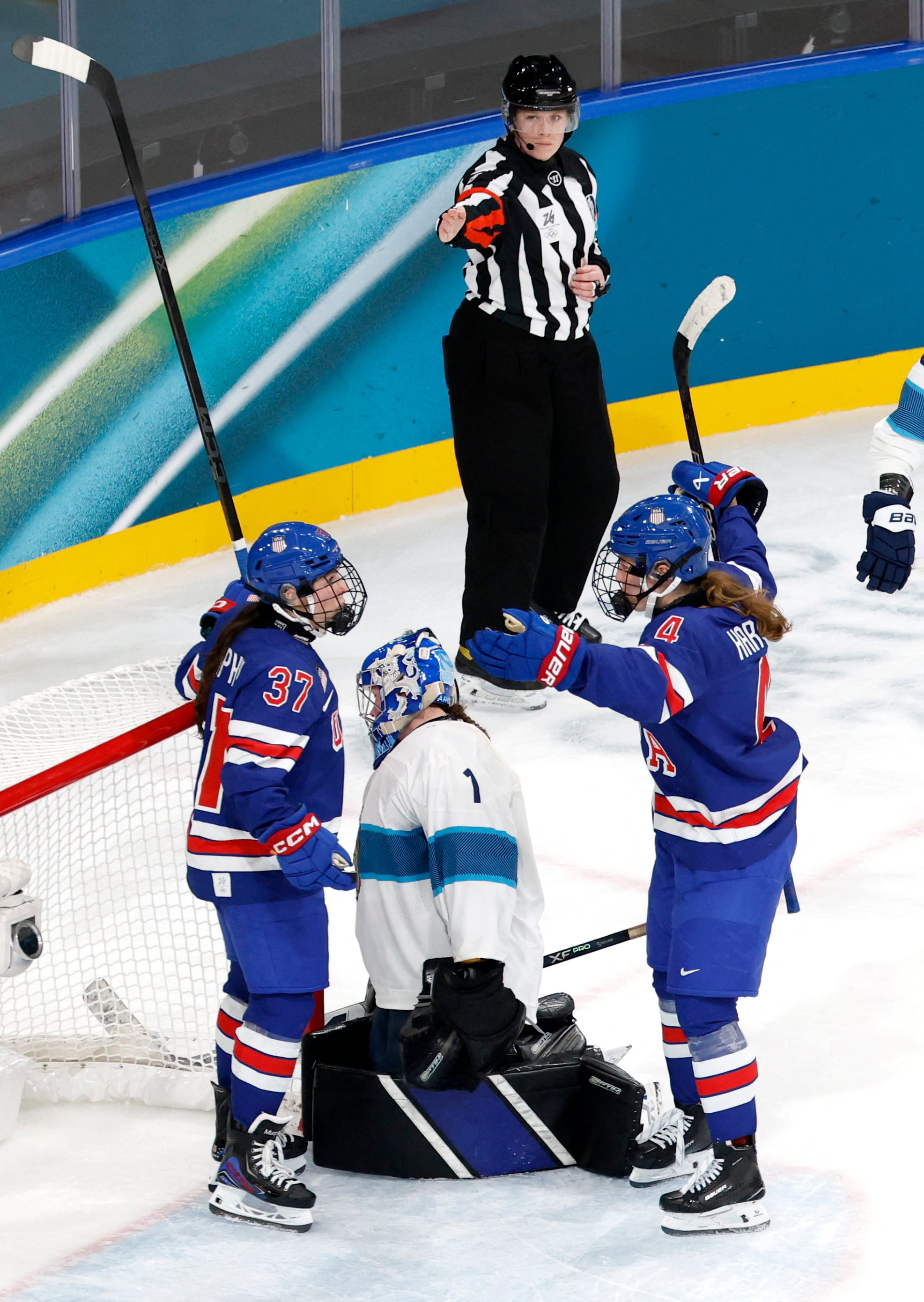 Murphy and Harvey celebrate a goal against Finland from inside the crease. They are both wearing blue home uniforms.