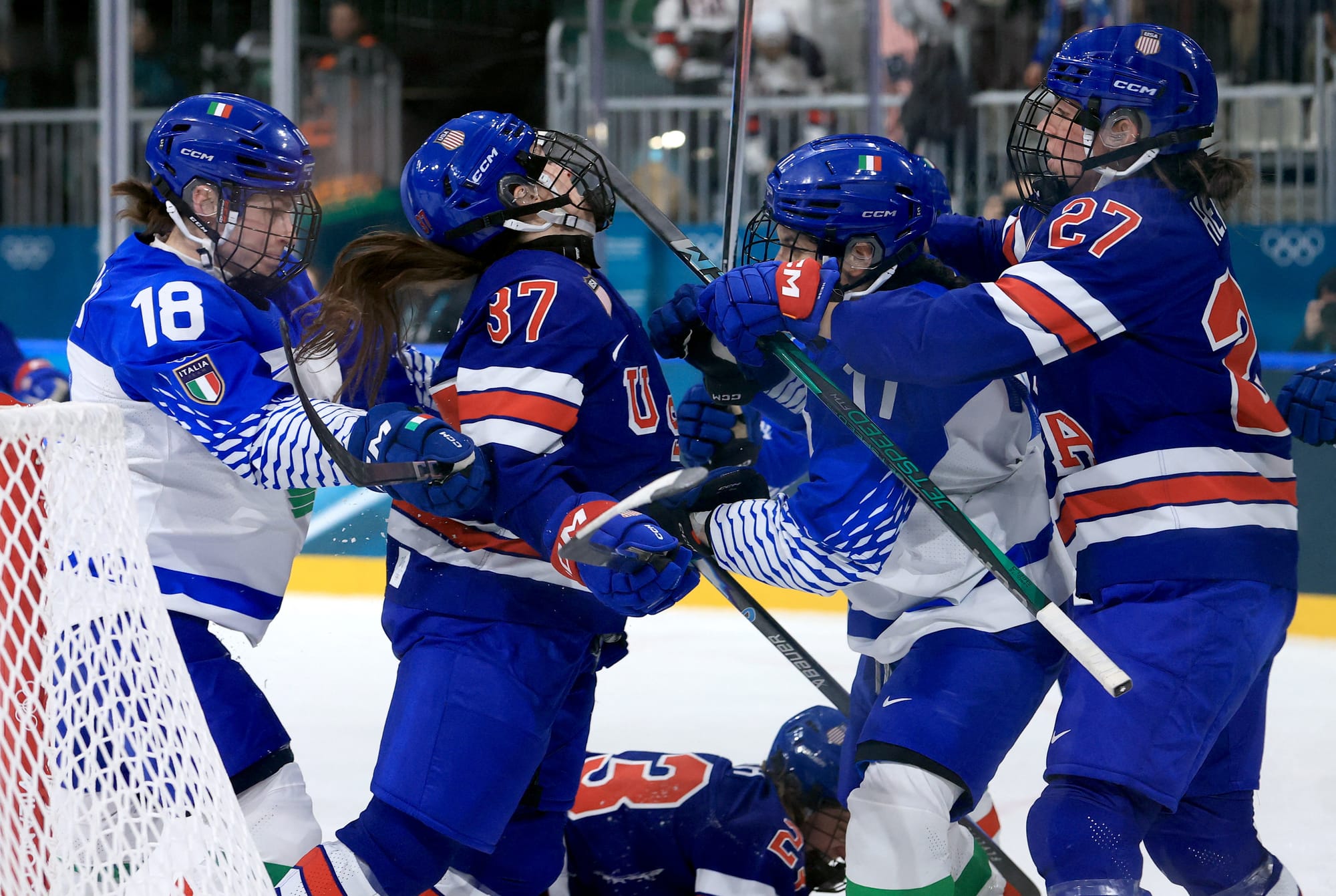 Members of Team USA and Team Italy shove each other following a U.S. goal. The Americans are in blue home uniforms, while the Italians are in white away ones.