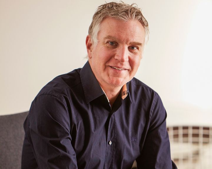 Michael Hirshfeld smiles at the camera. He has short grey hair and is wearing a navy blue shirt.