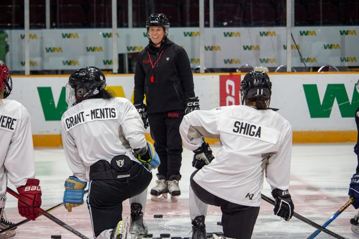 Grant-Mentis and Shiga kneel on the ice in front of head coach Carla MacLeod.