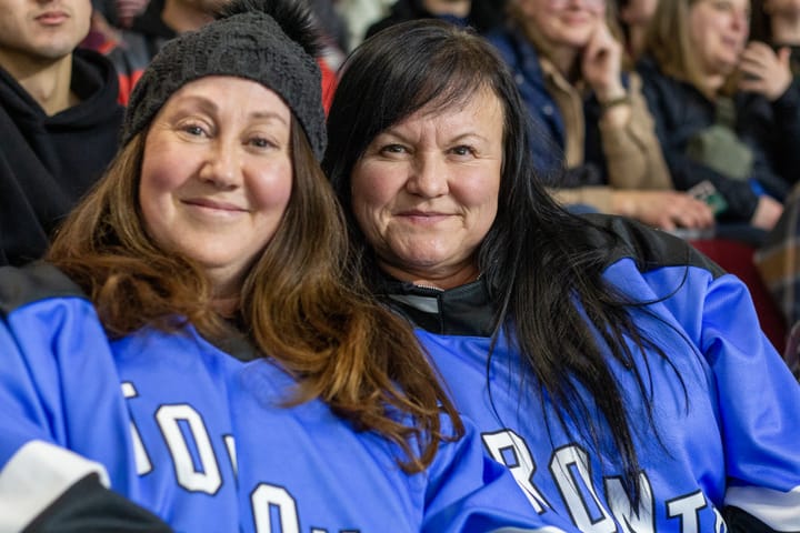 Two women wearing blue PWHL Toronto jerseys pose for a photo.