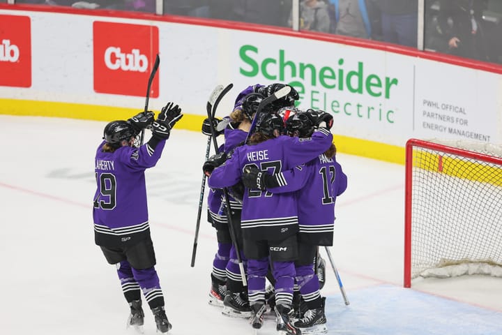 Minnesota players, wearing their purple home uniforms, celebrate their win over Toronto with goaltender Nicole Hensley.
